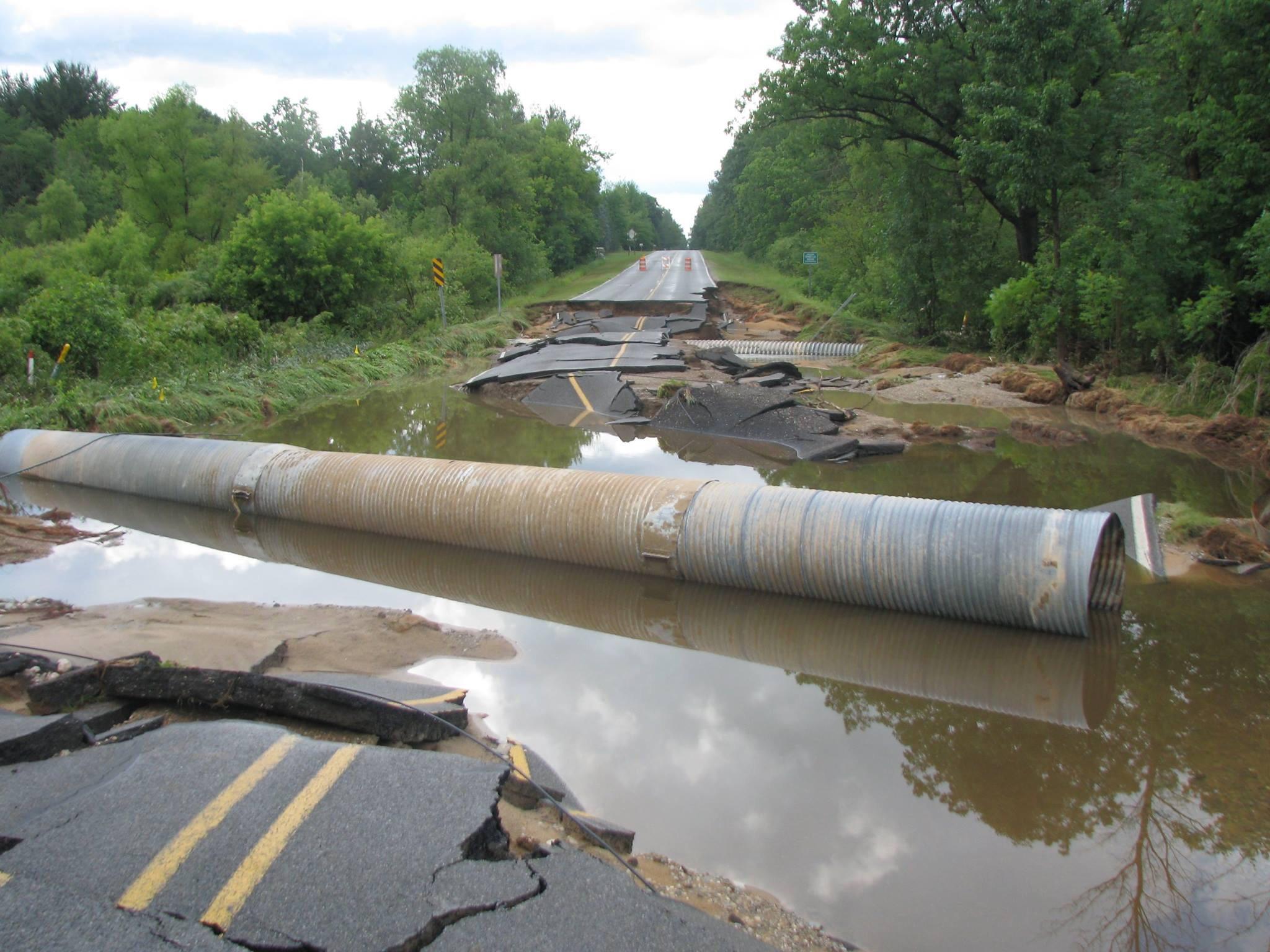 Large concrete culvert being installed with excavators and crew on a deep excavation site.