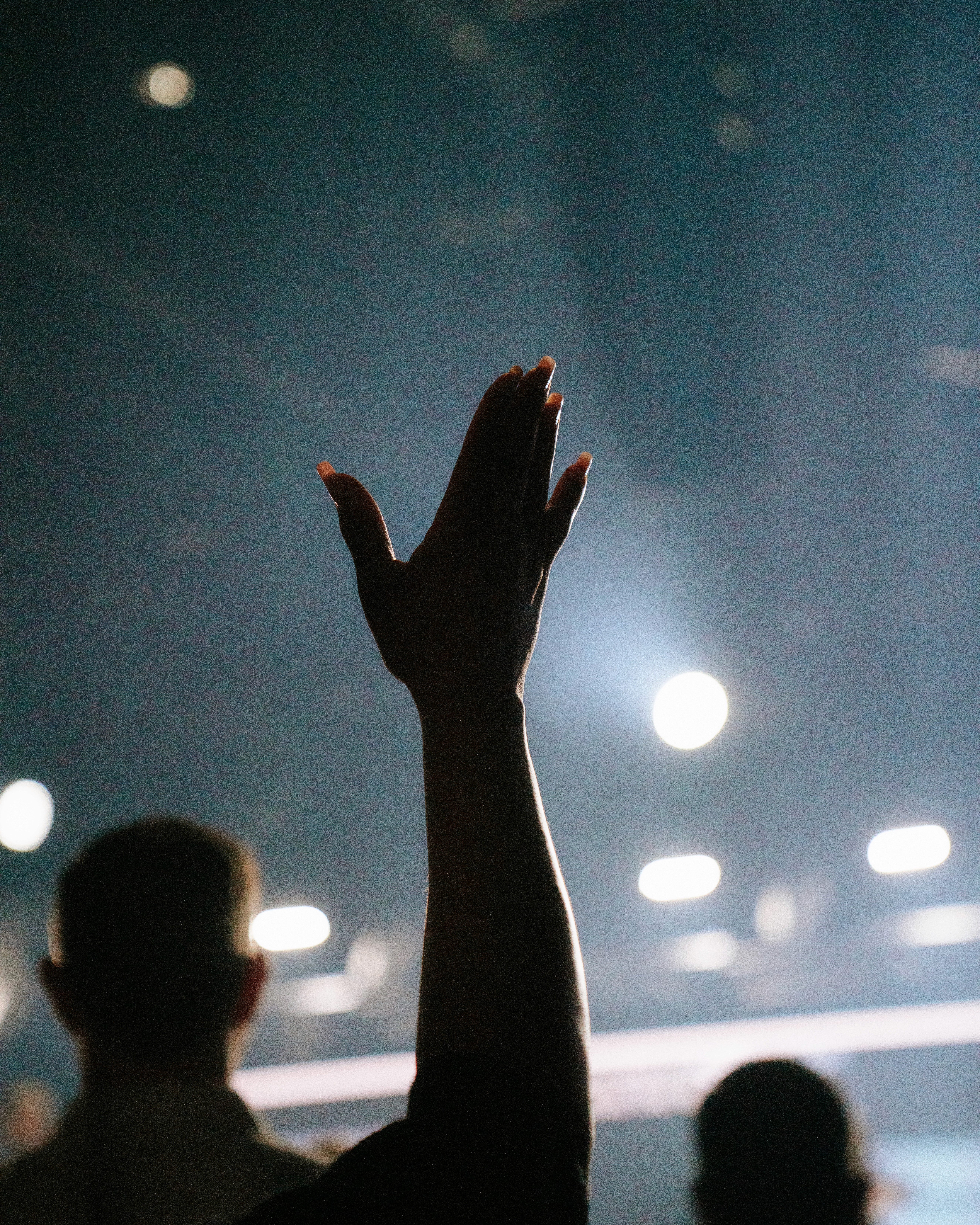 A drummer performing on stage, captured with dramatic lighting, focusing intently on playing the drums.