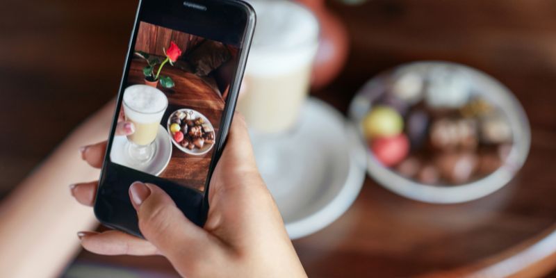 A woman taking a photo of her food and drink