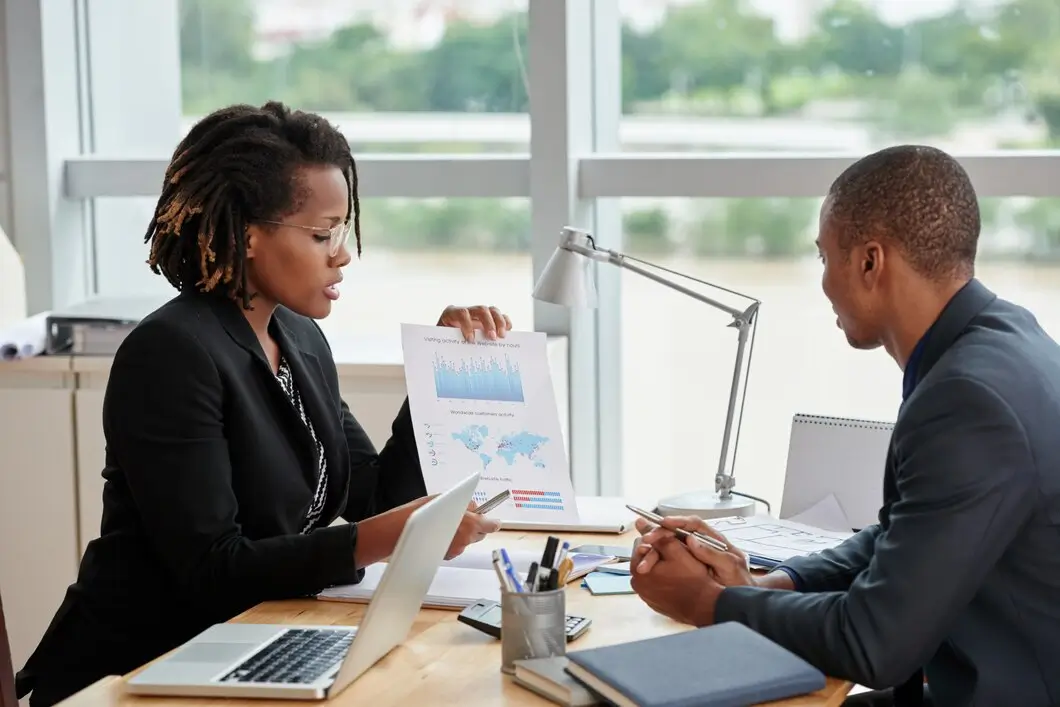 Black woman points to screen at meeting