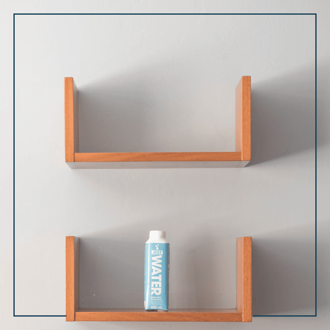 Zwei Wandregale untereinander, auf einem steht eine einsame Packung Wasser, das andere ist leer