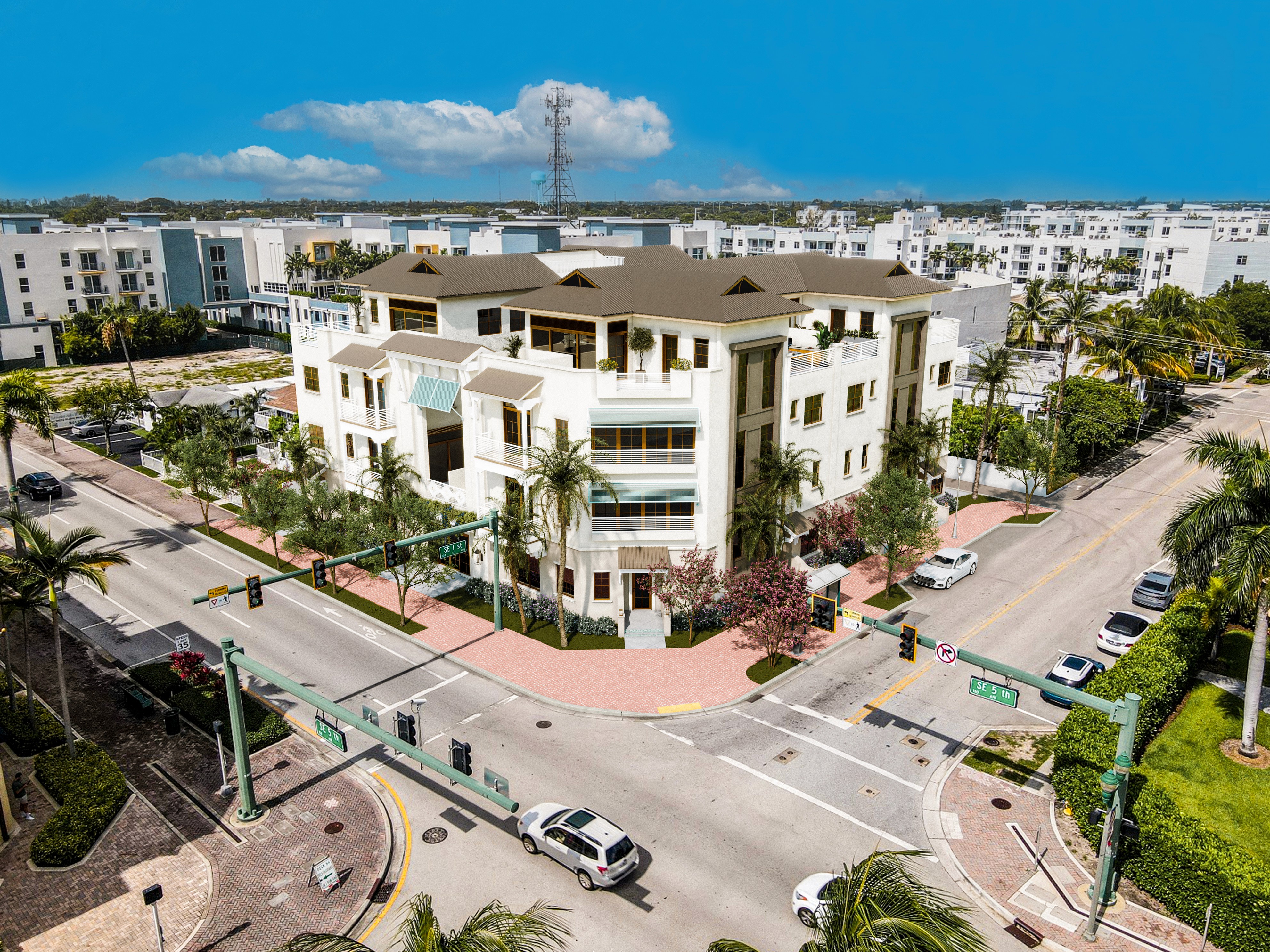 A bright aerial view of Casa Avenida showing a tan mid-rise at a palm-lined corner with crosswalks, cars, and modern apartments behind.