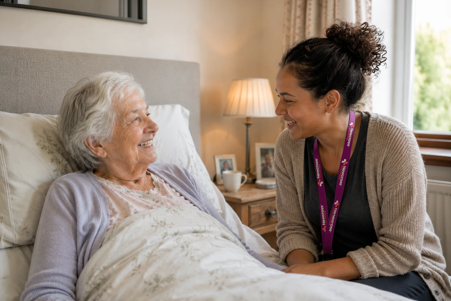 Elderly British woman smiling with a Newcross Healthcare carer while receiving compassionate care at home