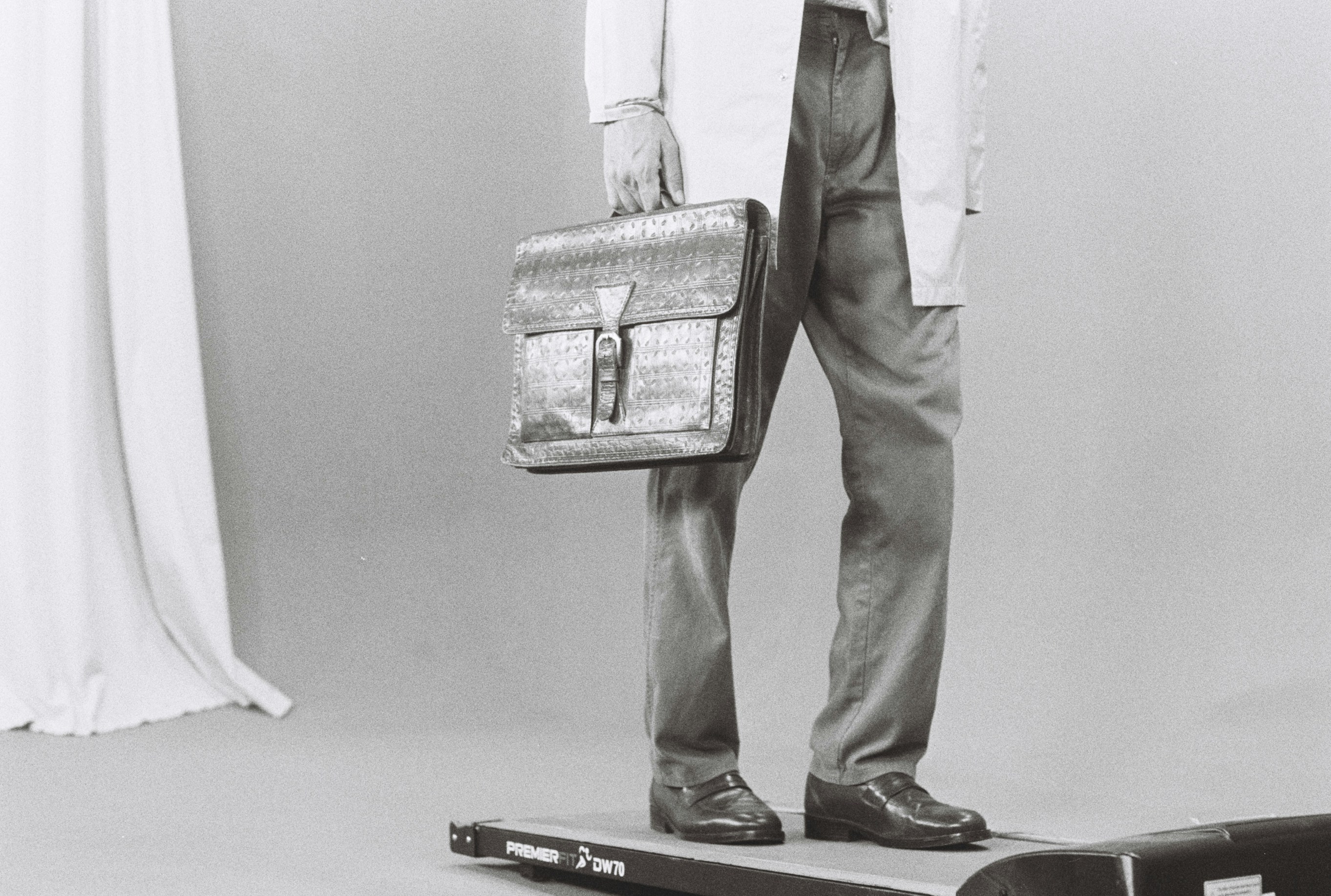 Man in lab coat holding briefcase on scale