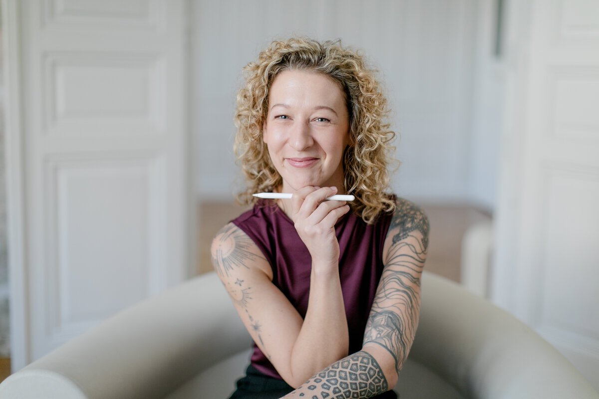 Portrait von Sandra Kitting, UI/UX-Designerin in Wien, mit Stift in der Hand und lachendem Ausdruck