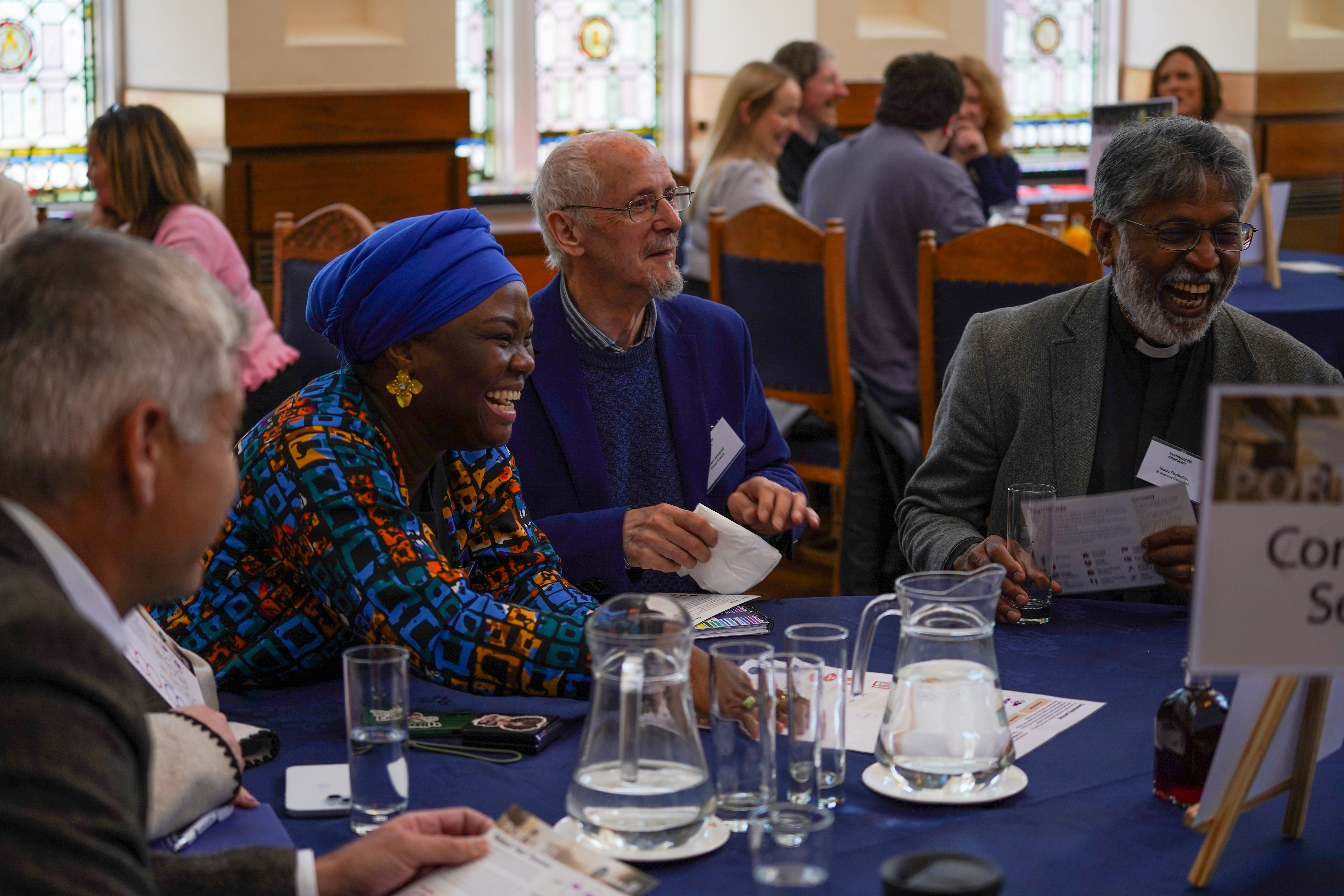A group of veterans stand to attention in front of a wall of poppies as part of a Remembrance Day event