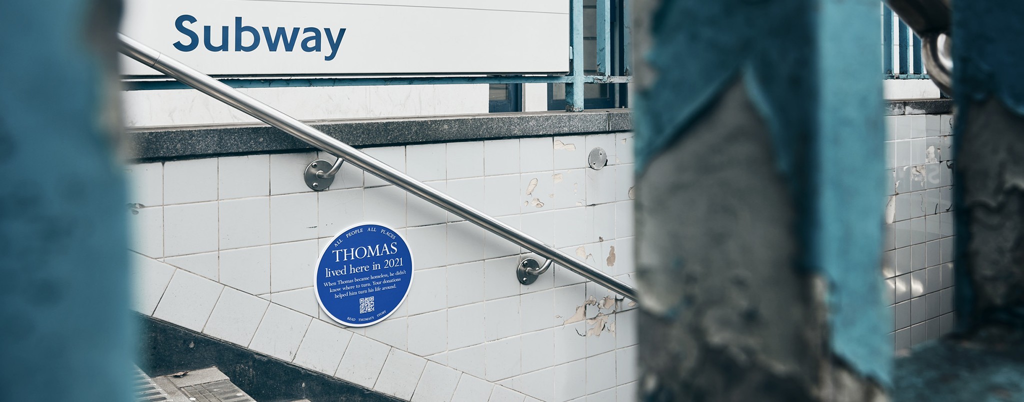 Blue plaque on the wall of a subway staircase of the London underground