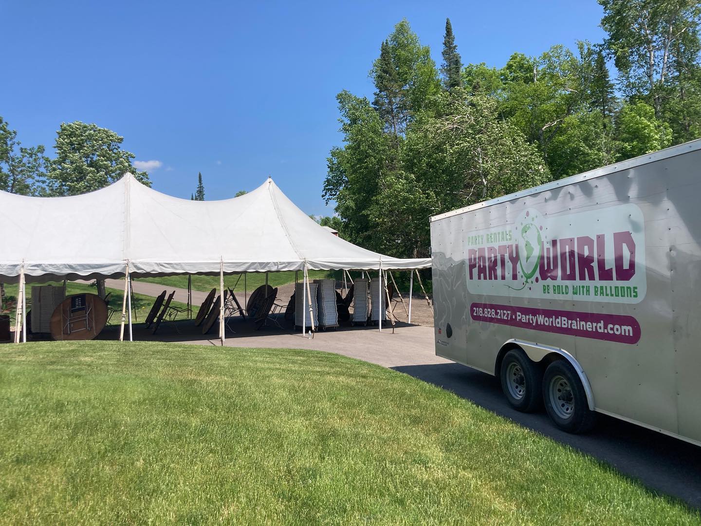 Large white event tent set up on grass beside the Party World trailer and Be Bold Balloons van