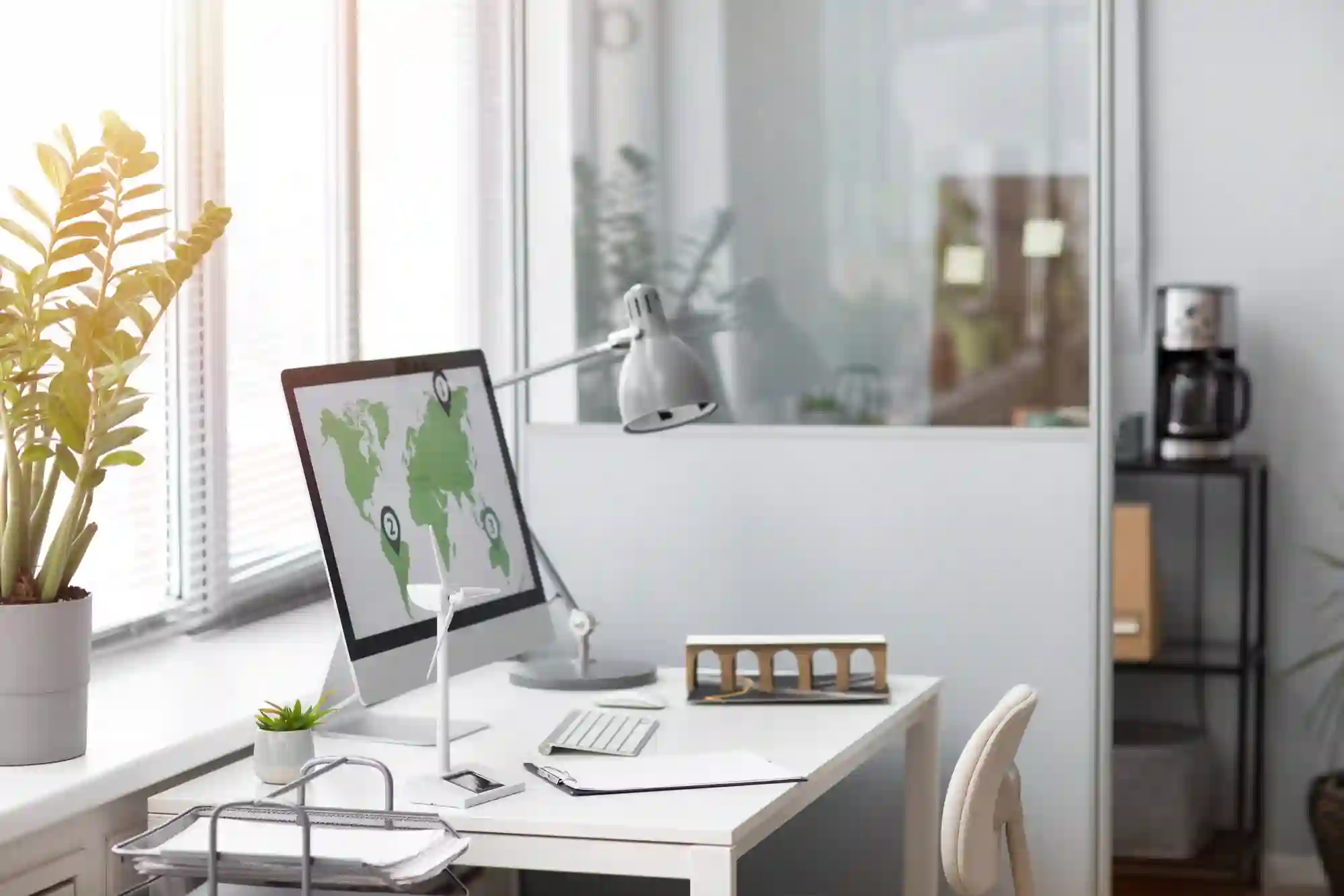A bright, modern office workspace featuring a computer displaying a world map, emphasizing global connectivity and remote work.