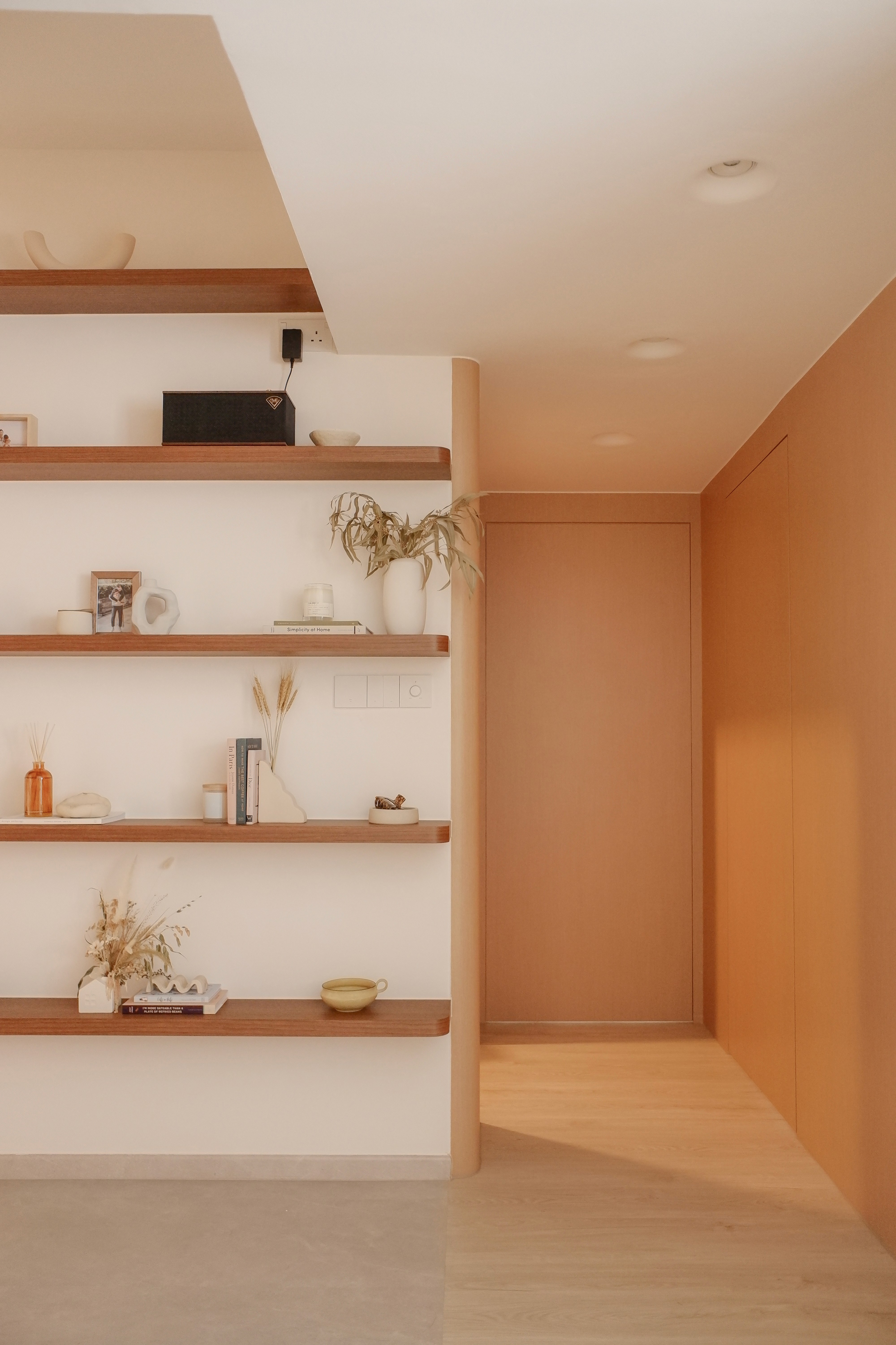 Custom-built hallway with concealed doors and wooden wall paneling, modern HDB renovation Singapore"