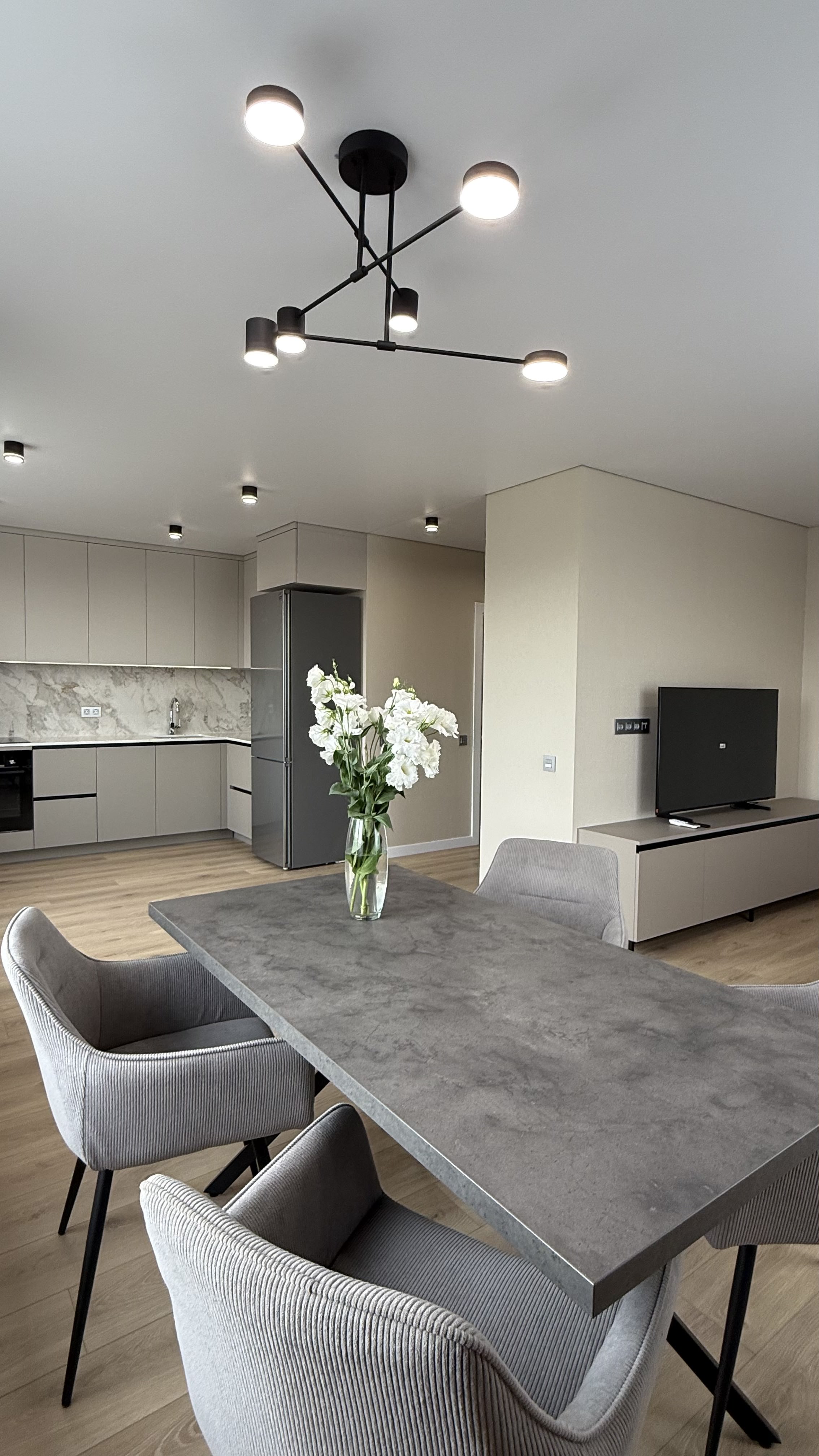 Обідня зона з квітами у вазі та відкритою кухнею на задньому плані