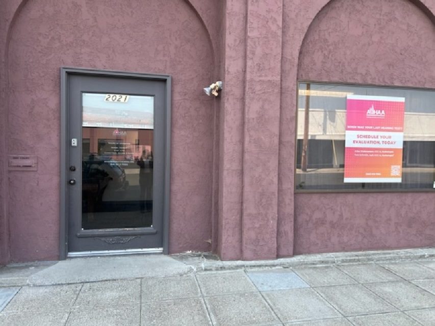 Winding hiking trail through grassy mountainside with trees.
