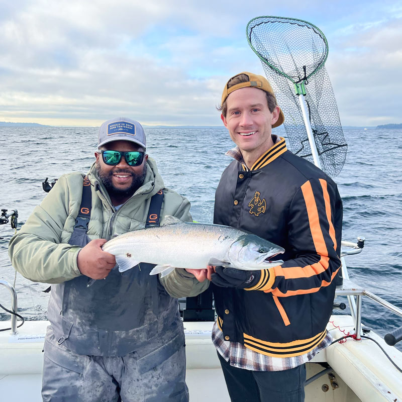 Captain and guest holding freshly caught coho salmon