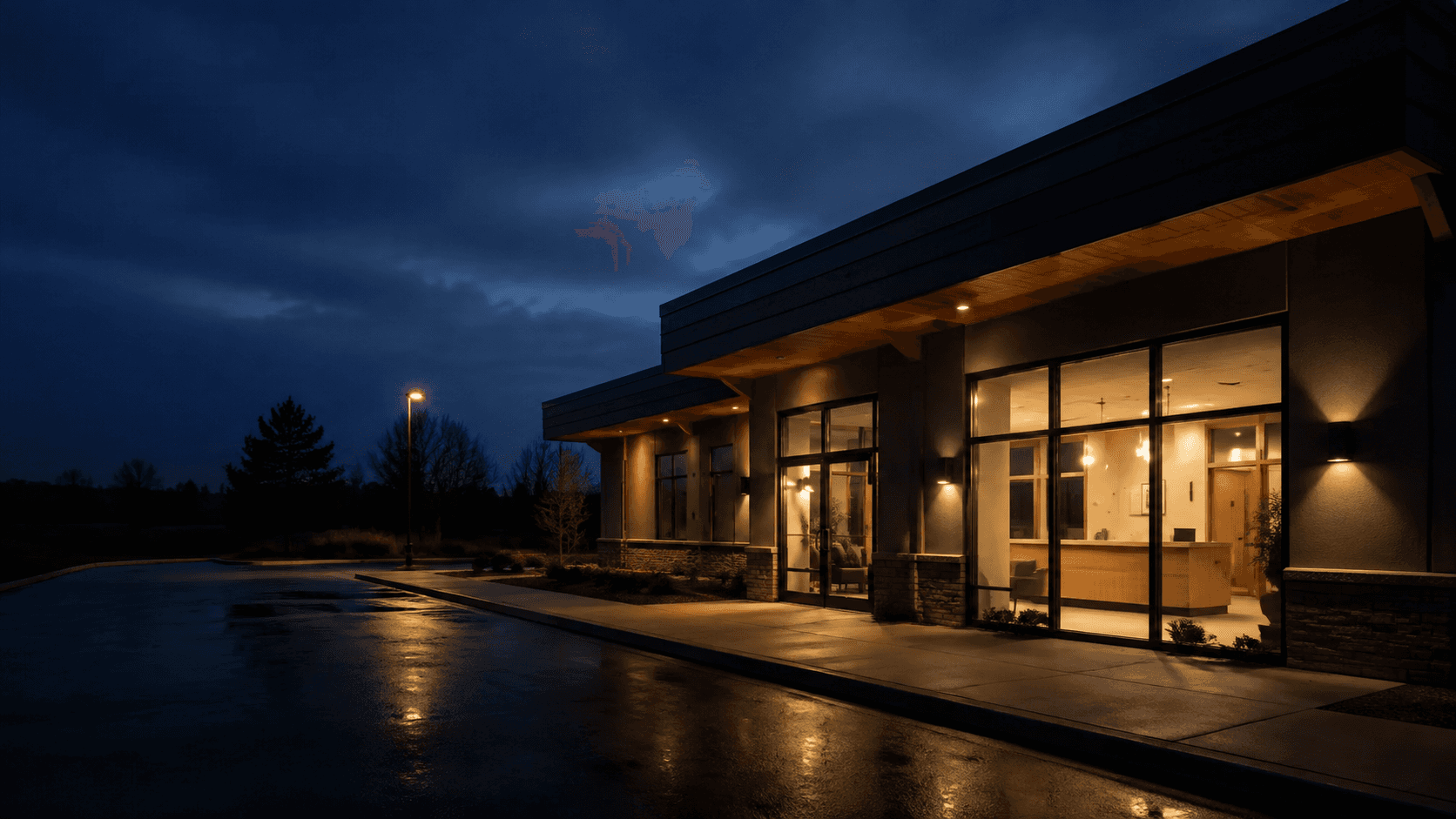 Illustrative neighborhood clinic at dusk with a warmly lit reception.