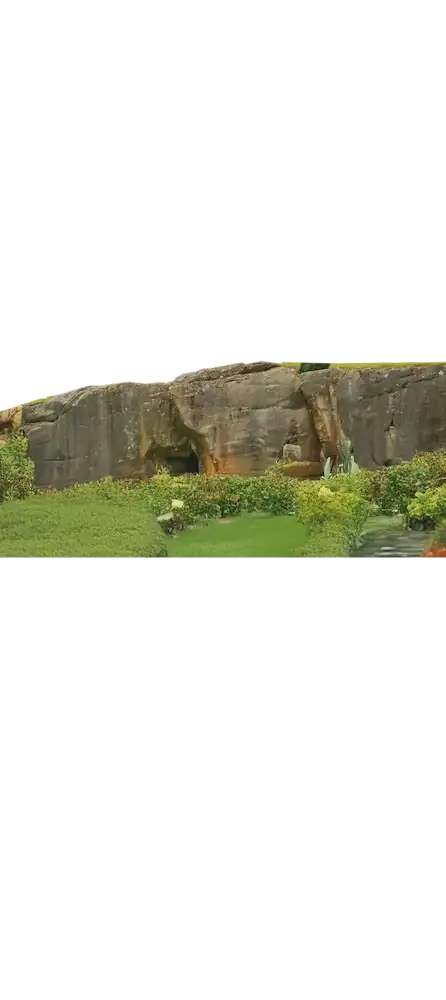 Large horizontal rock formation surrounded by carefully maintained vegetation, blending raw stone and garden design.
