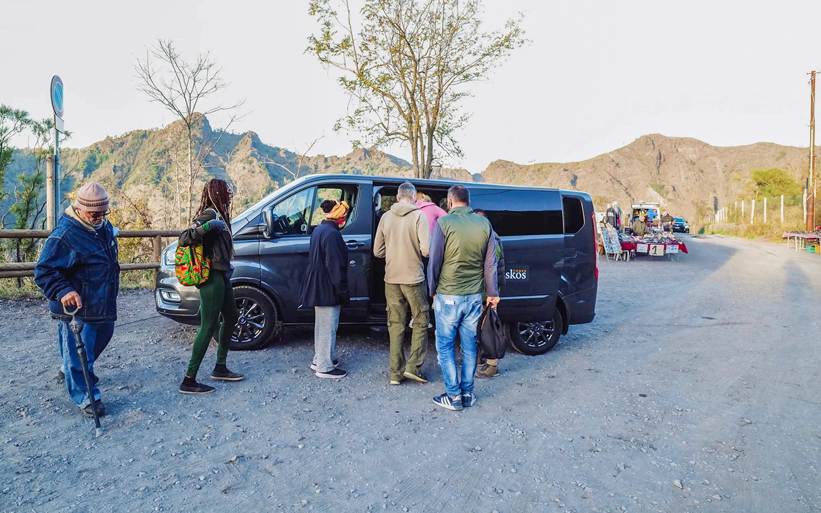 一群游客正在山区登上一辆配备专业司机的商务车。