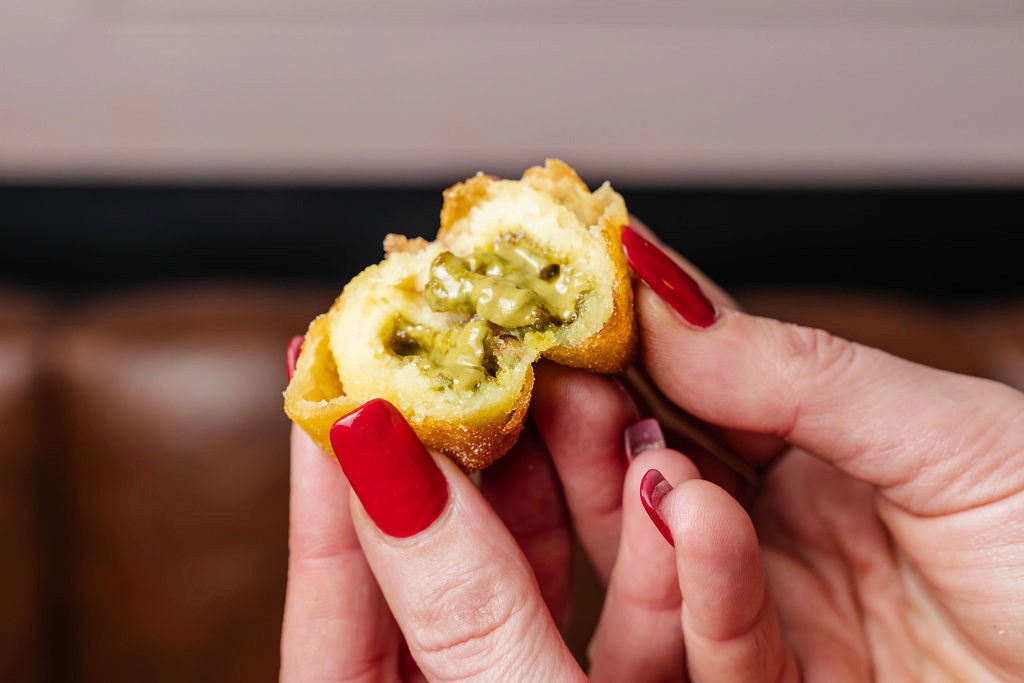 a glass of cocktail with a slime orange fruit