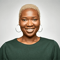 A Black woman with short cropped hair and hoop earrings, smiling straight at the camera in a studio portrait (black-and-white).