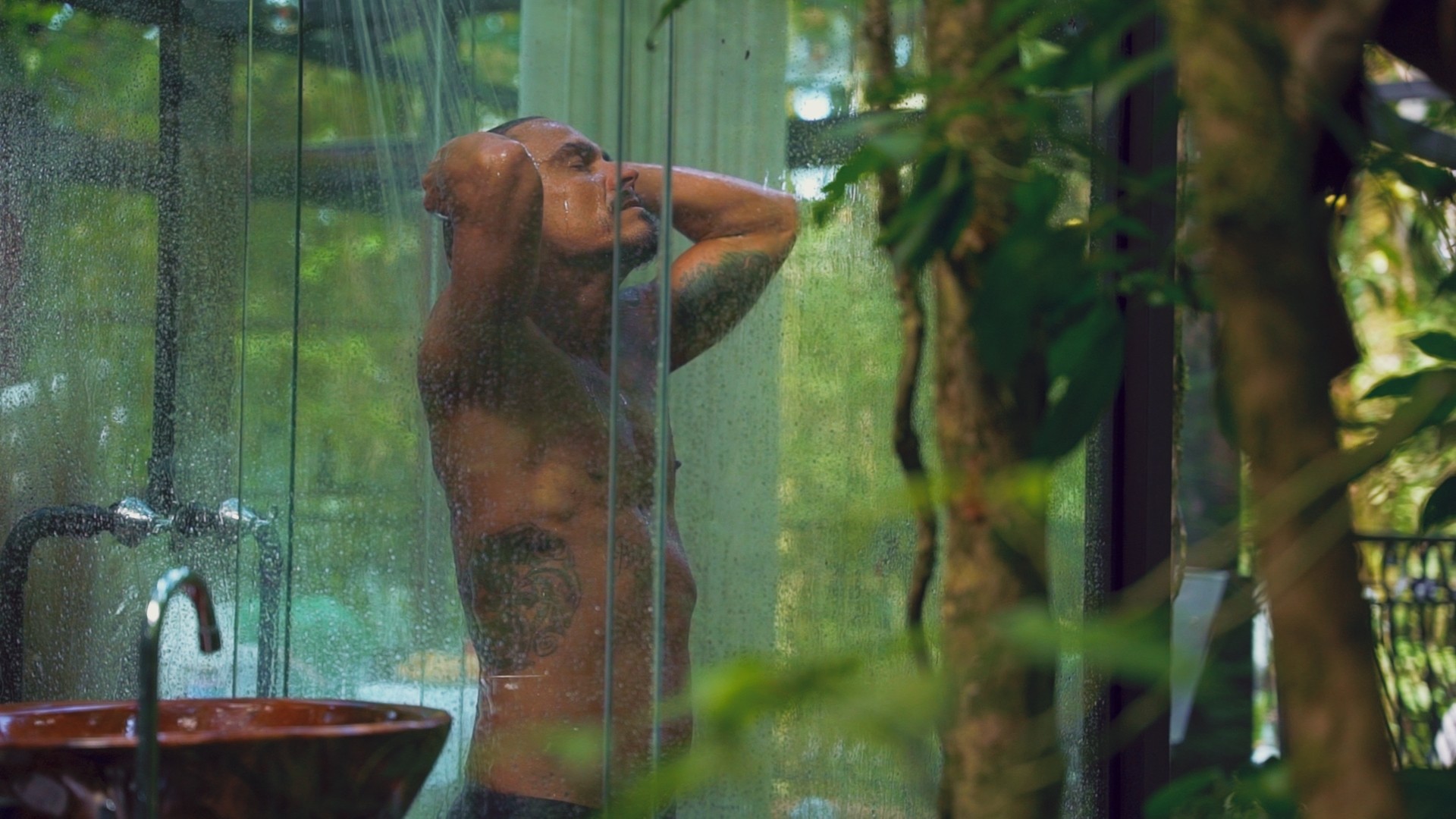 Modelo masculino tomando banho ao ar livre em produção audiovisual em Guabiruba para o Chalé Cristal