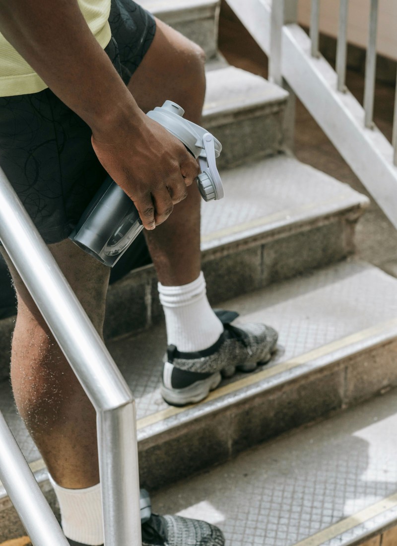 Man standing on outdoor staircase holding water bottle