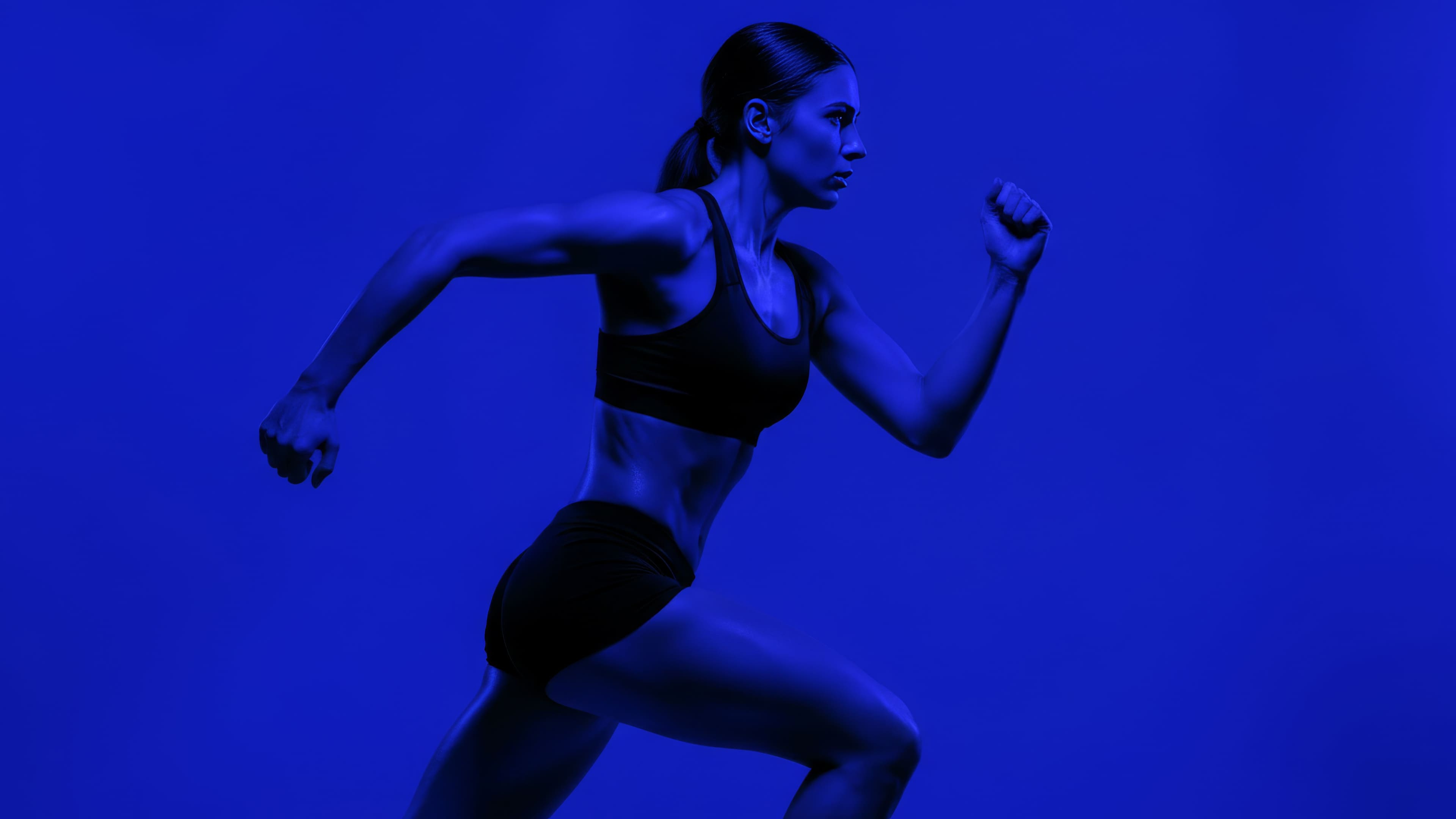 Side profile of a woman running in motion, with a blue background highlighting her athletic form.
