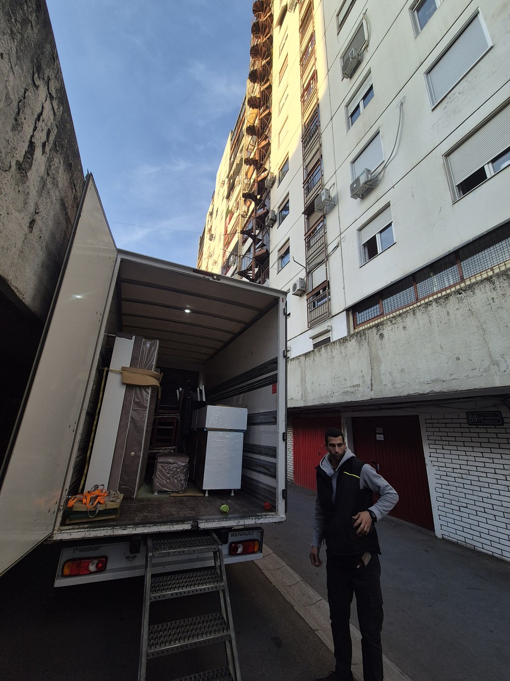 Utovar nameštaja u kamion za selidbu ispred stambene zgrade — profesionalna ekipa za selidbe pažljivo pakuje i transportuje stvari