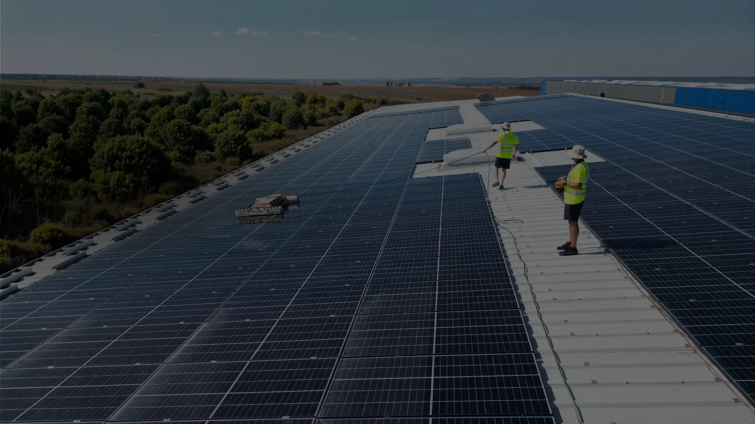 Echipă SpalPanouri curățând panouri fotovoltaice pe acoperiș industrial