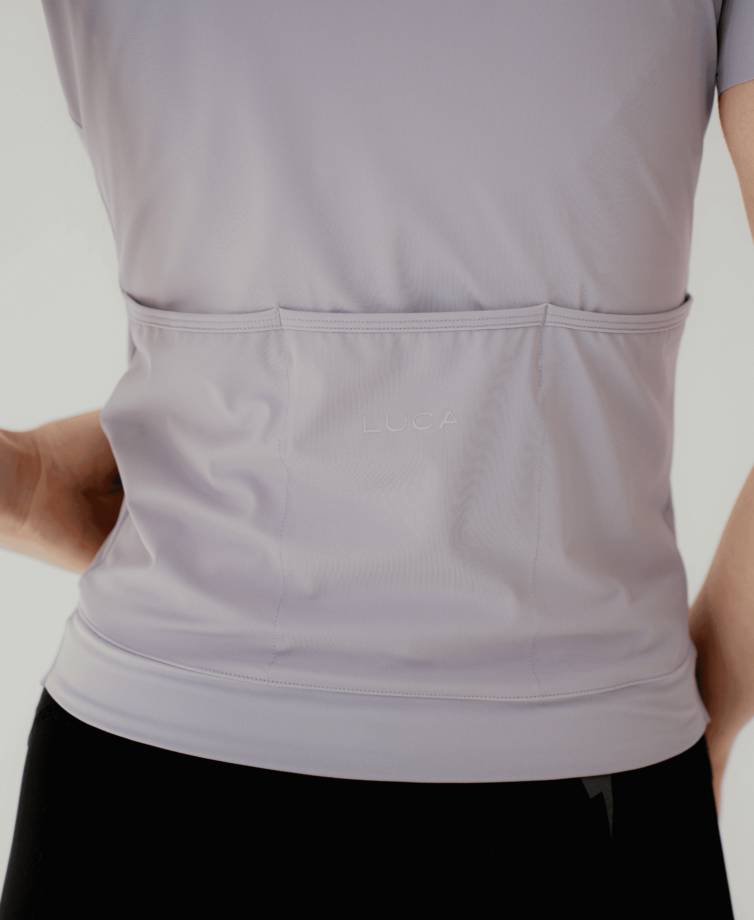 Close-up-back-view-of-the-lavender-cycling-jersey-clearly-showng-the-three-back-pockets-and-the-subtle-embroidered-LUCA-logo-centered-above-the-pockets