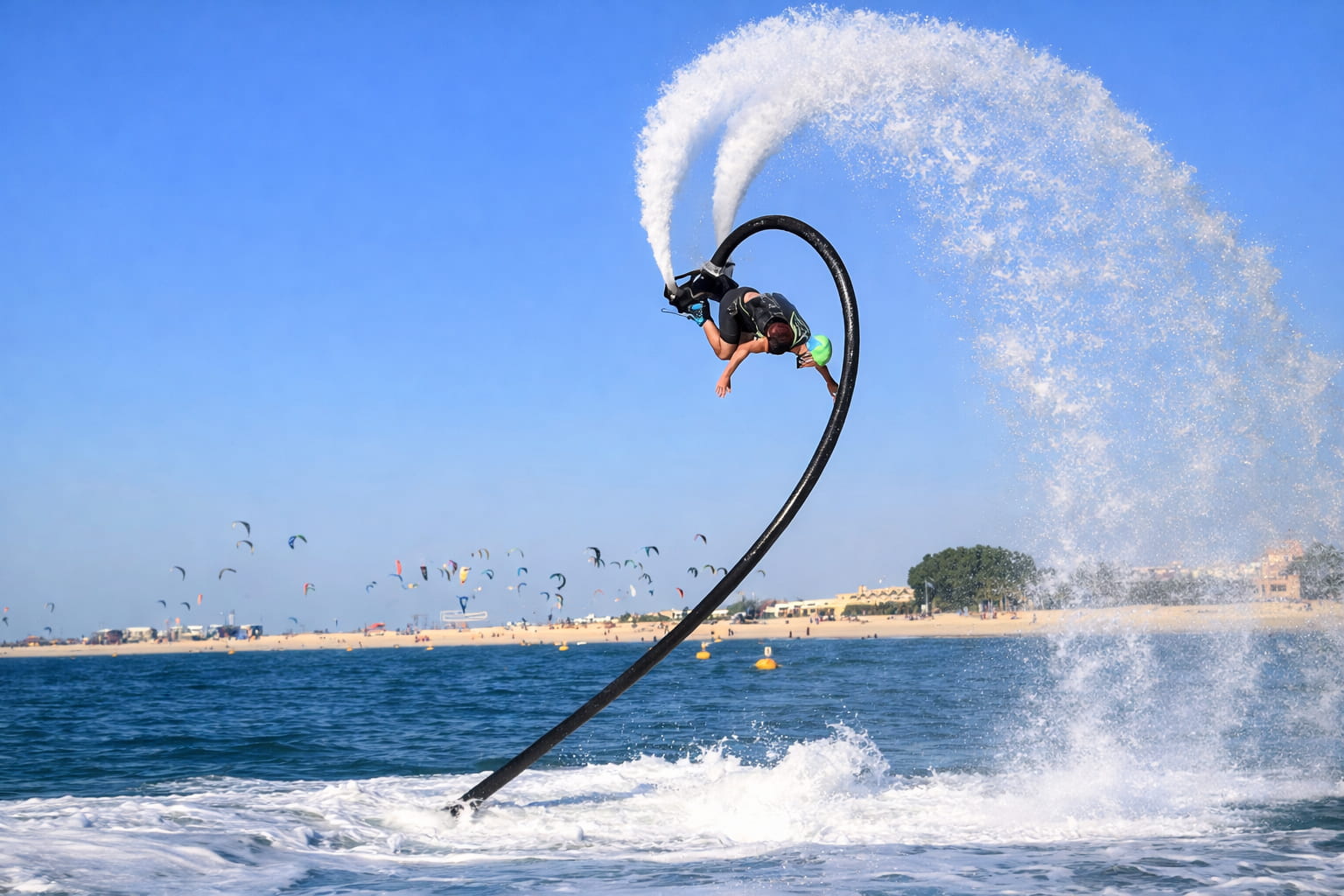 A man performing flyboarding tricks in the water with a beach in the distance during things to do in Dubai with family.