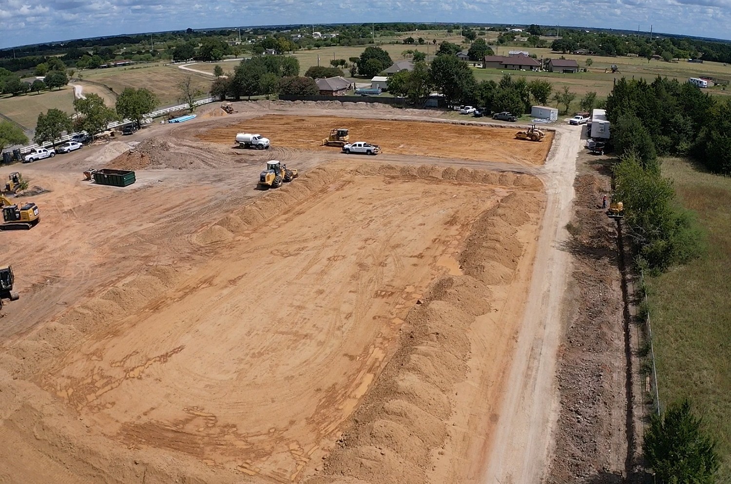 Aerial view of commercial building pad grading and site preparation with excavation equipment on development site in the Kansas City area.