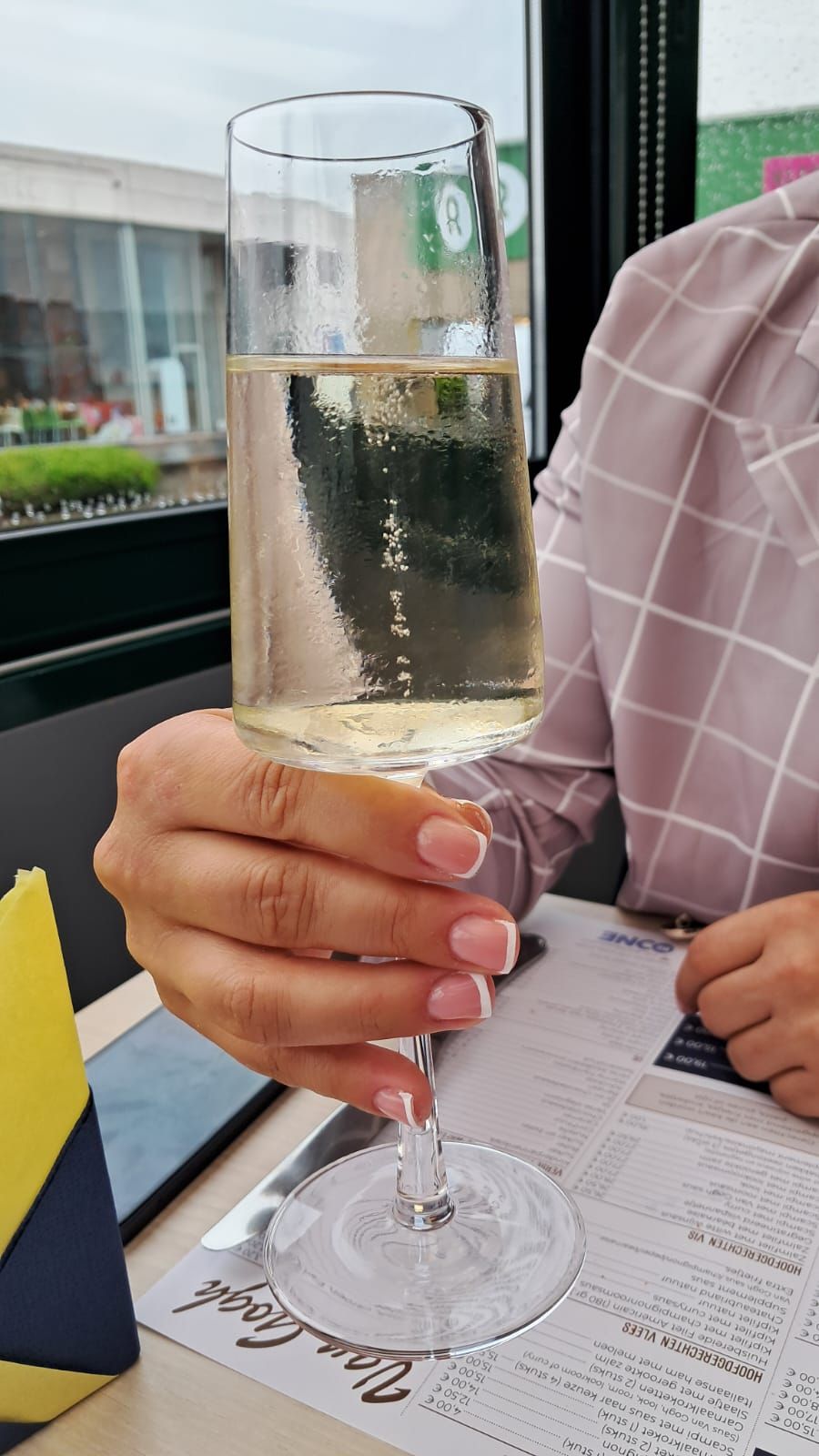 Hand with light pink nails and rings on cozy blanket