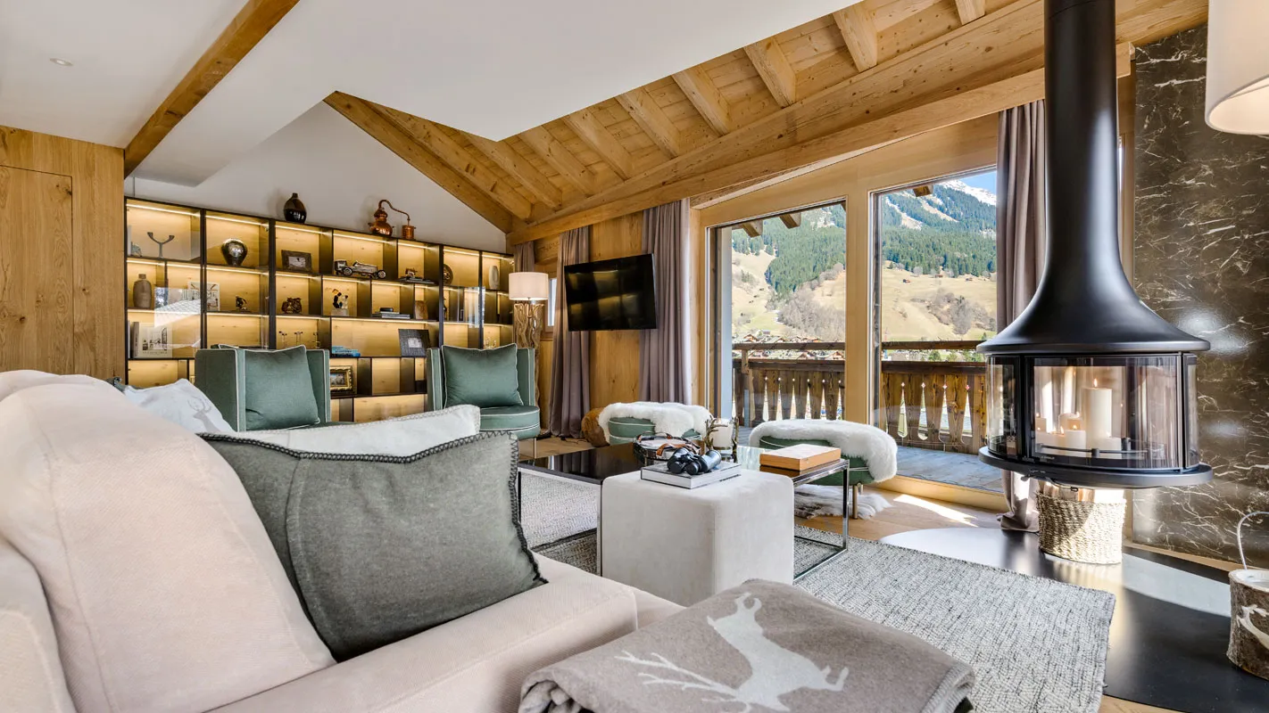 Silvretta Klosters living room with suspended fireplace, backlit display shelving, and balcony doors to the Swiss Alps