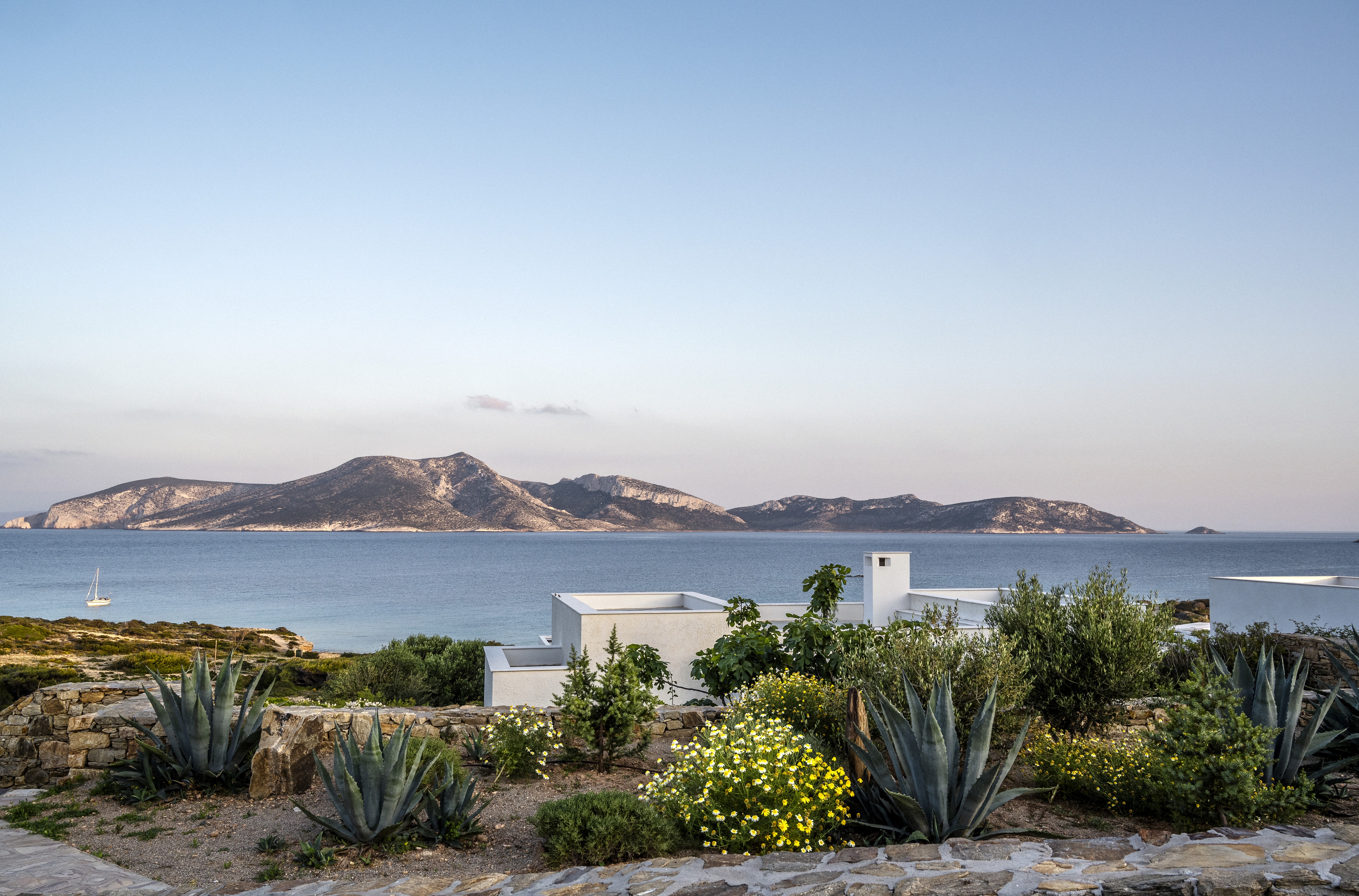 White house with blue skies and lush gardens in Koufonisia Greece overlooking de Aegan sea and the island of Keros