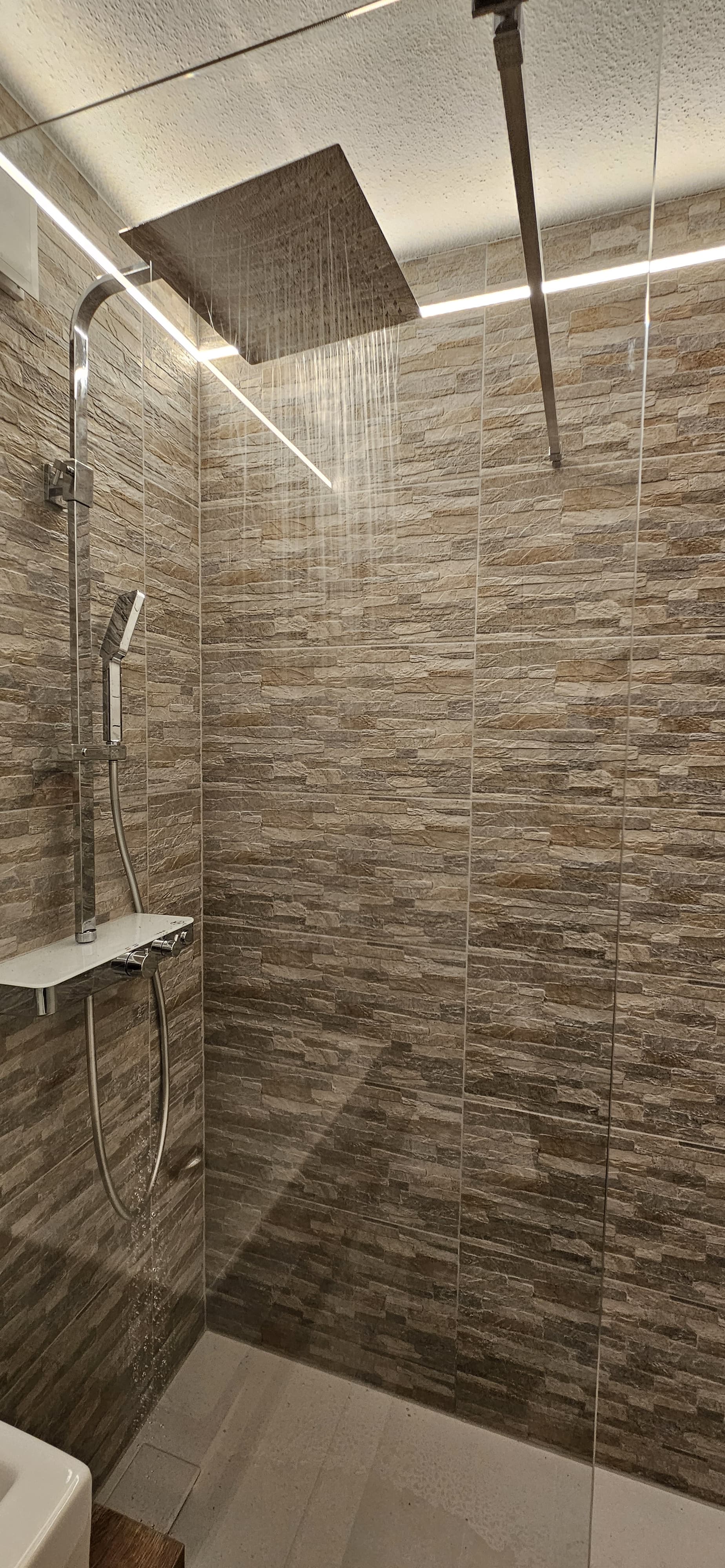 Large house with a wrap-around balcony overlooking a lit pool and deck at night.