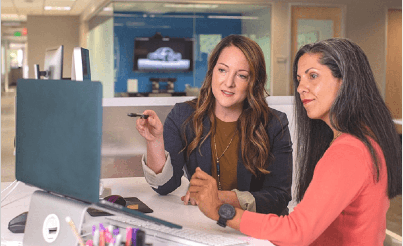 Two professionals discussing a performance consulting plan, reviewing work together in an office setting.