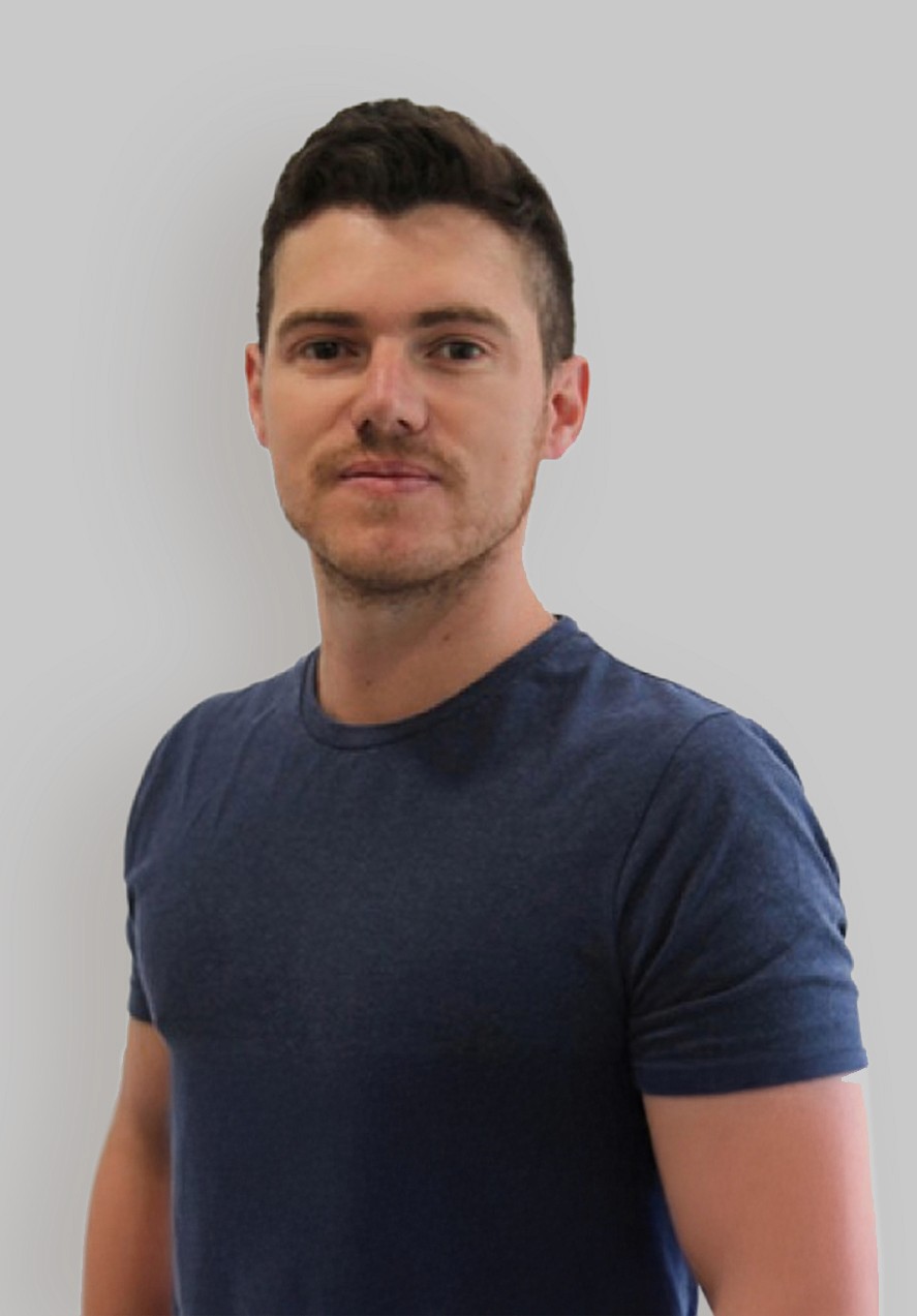 A young man in a white t-shirt stands against a light-colored background.