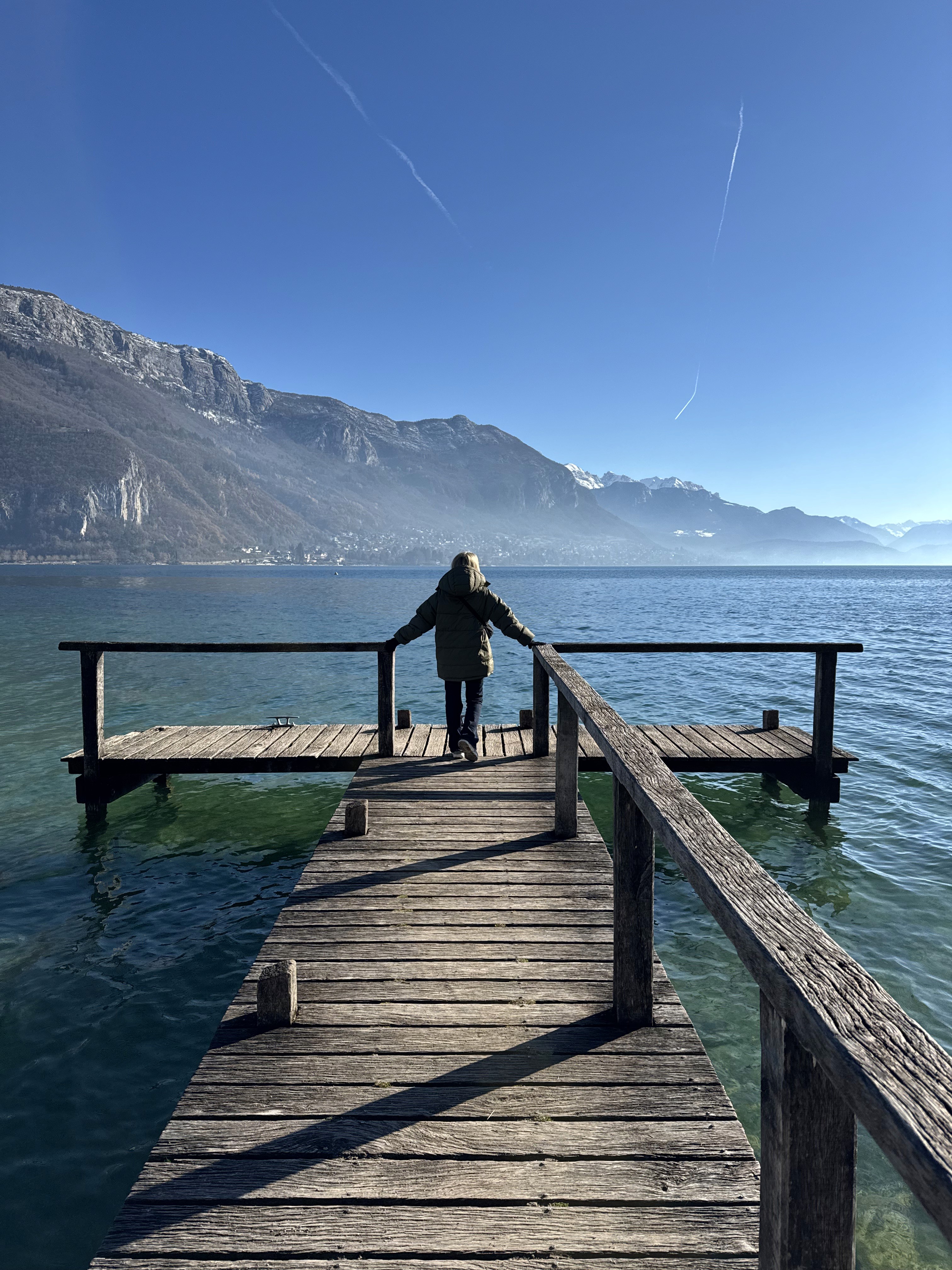 A luxurious indoor pool area with a panoramic view of a city at sunset. Comfortable lounge beds with soft fabrics surround the pool, while warm ambient lighting enhances the sophisticated atmosphere. The space combines modern elegance with a tranquil vibe.