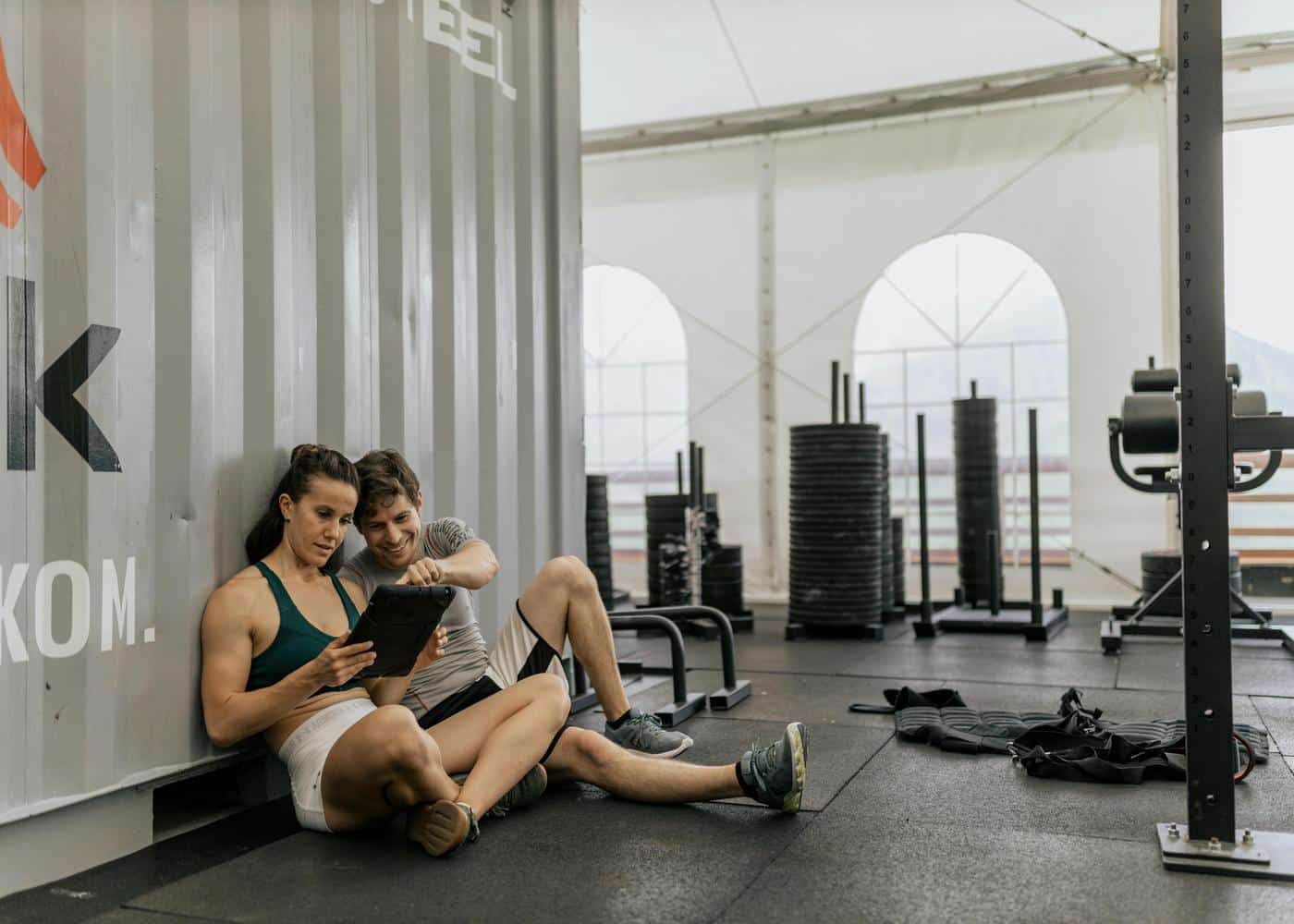 Couple sitting on floor at gym looking at tablet