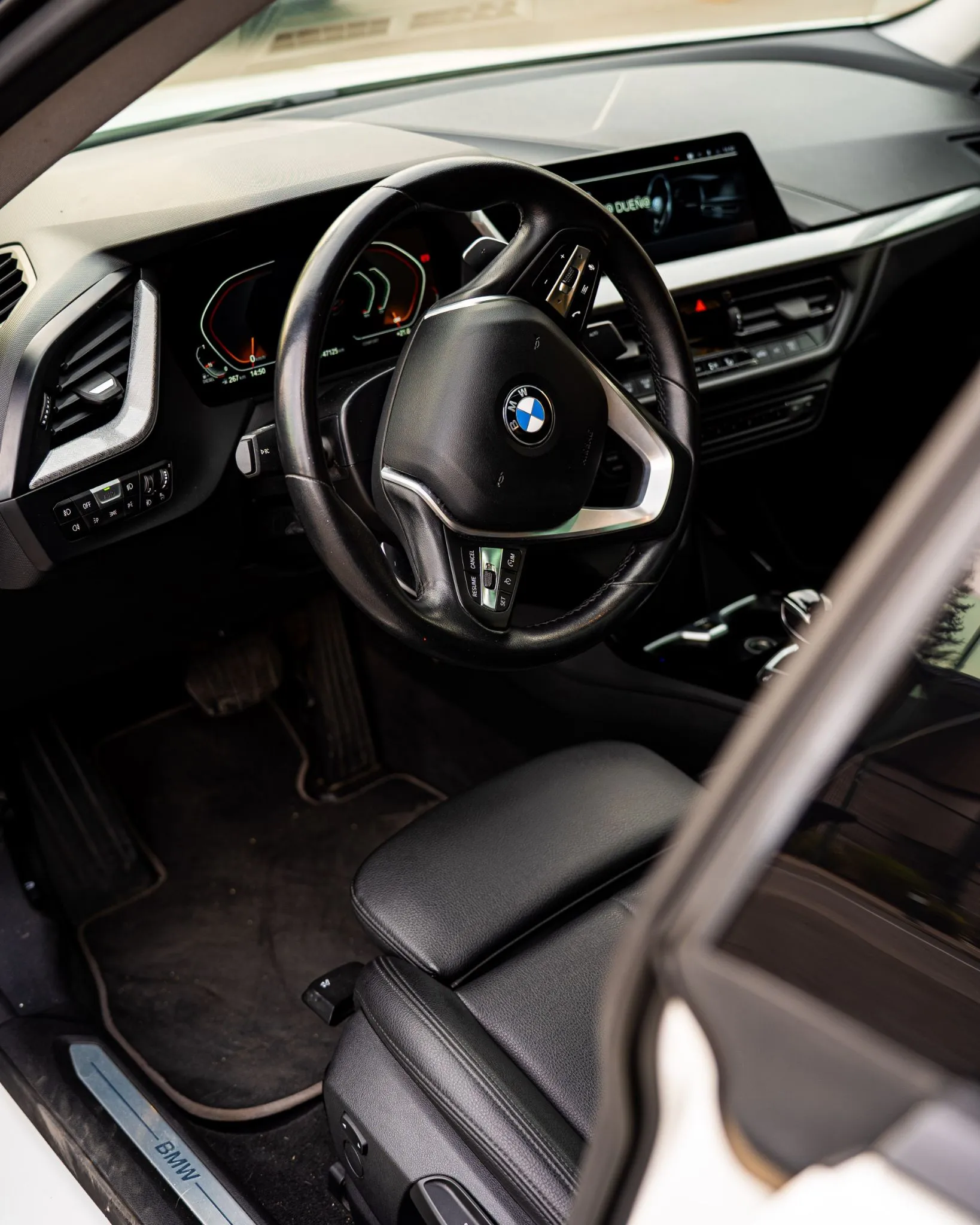 Interior del BMW 220d con volante, tablero digital, pantalla central y asiento delantero negro