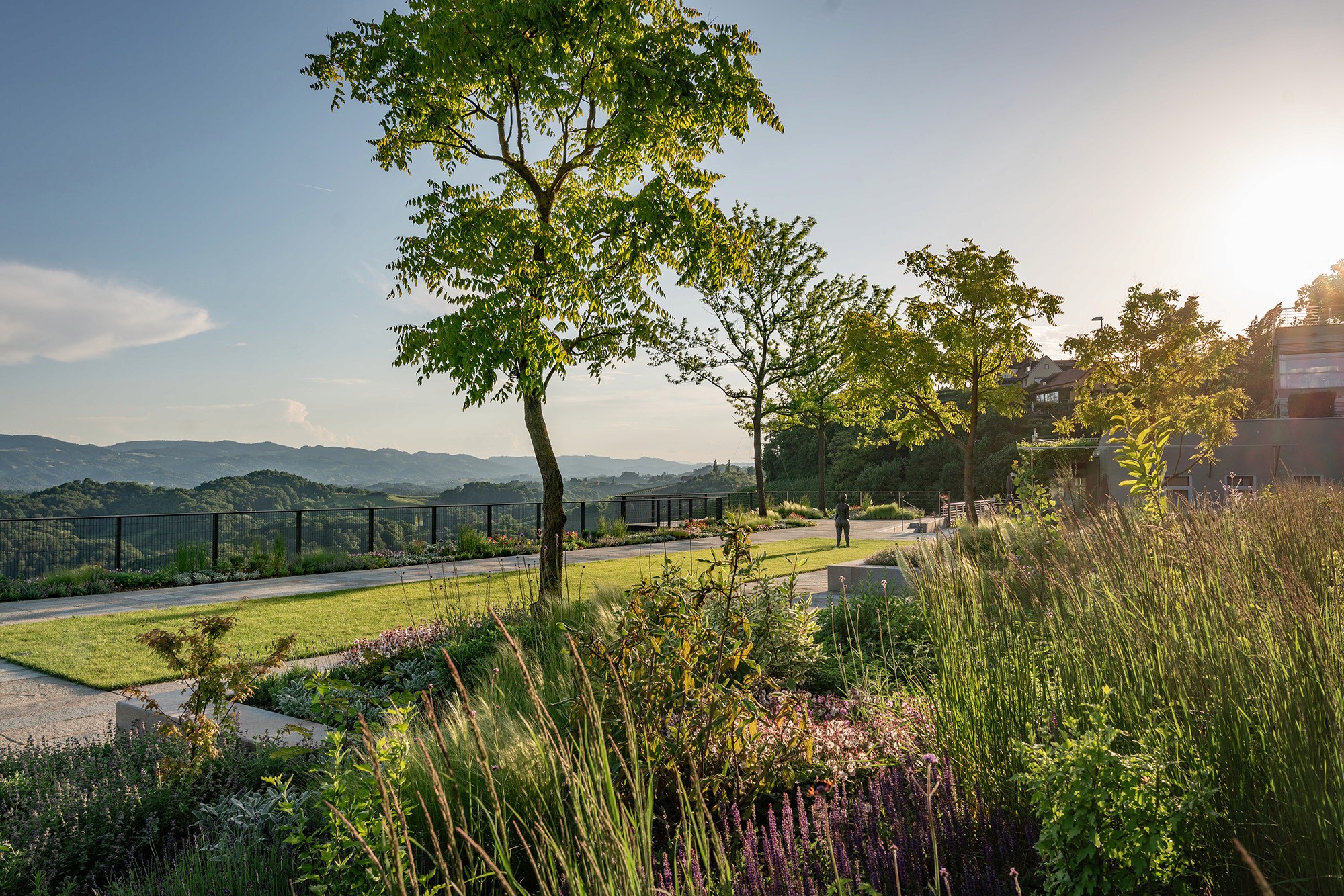 Großzügiger Garten mit Rasenfläche, Staudenbeeten und weitem Blick über die Landschaft.