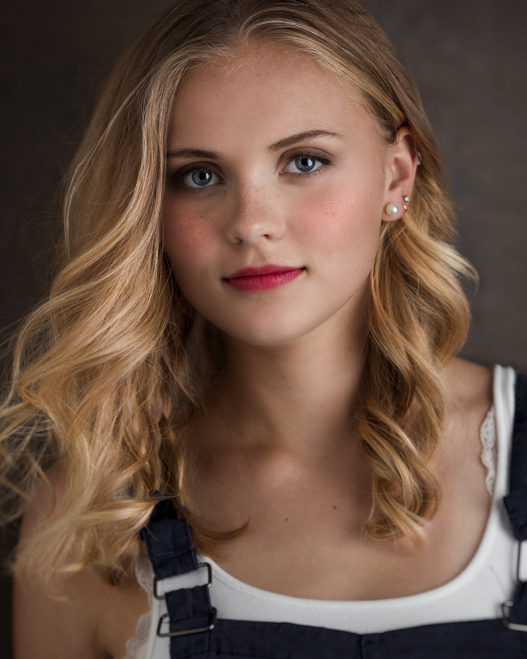 Simple, close up portrait of Olivia in overalls in the studio.