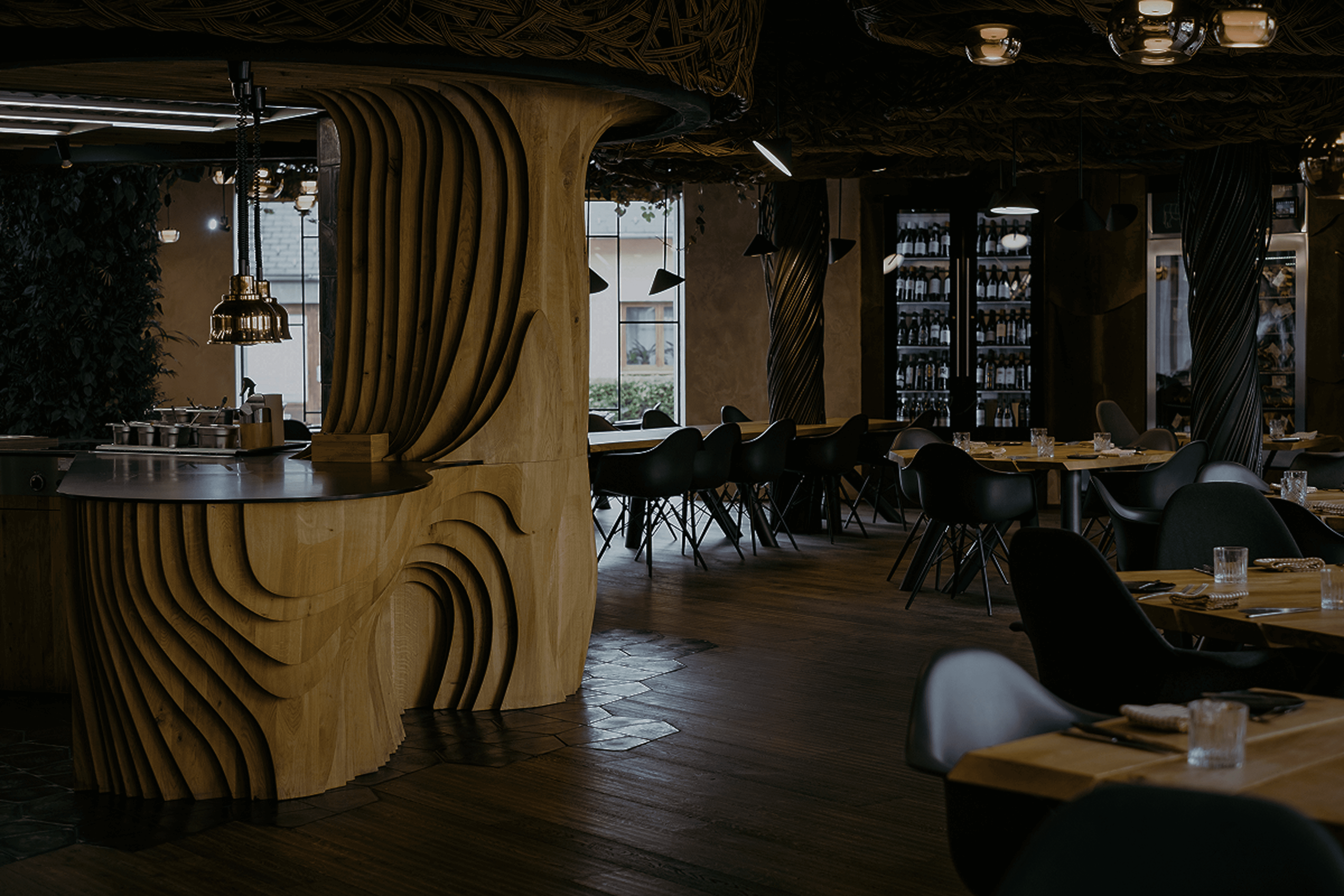 Stylový interiér moderní restaurace s originálním dřevěným designem, kulatými prvky a černými židlemi.