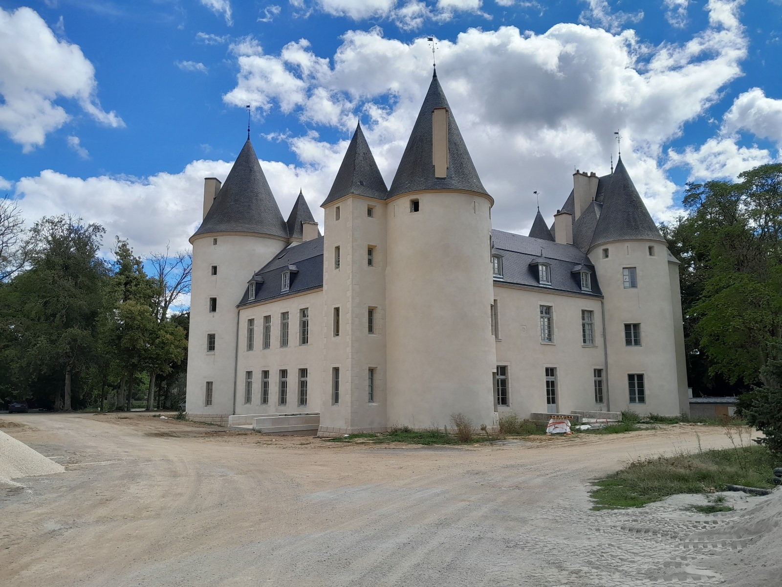 Vista externa de um castelo histórico com torres e arquitetura medieval sob um céu azul com nuvens, exemplificando a especialização da TCC Especialização em restauração e preservação de edificações históricas.