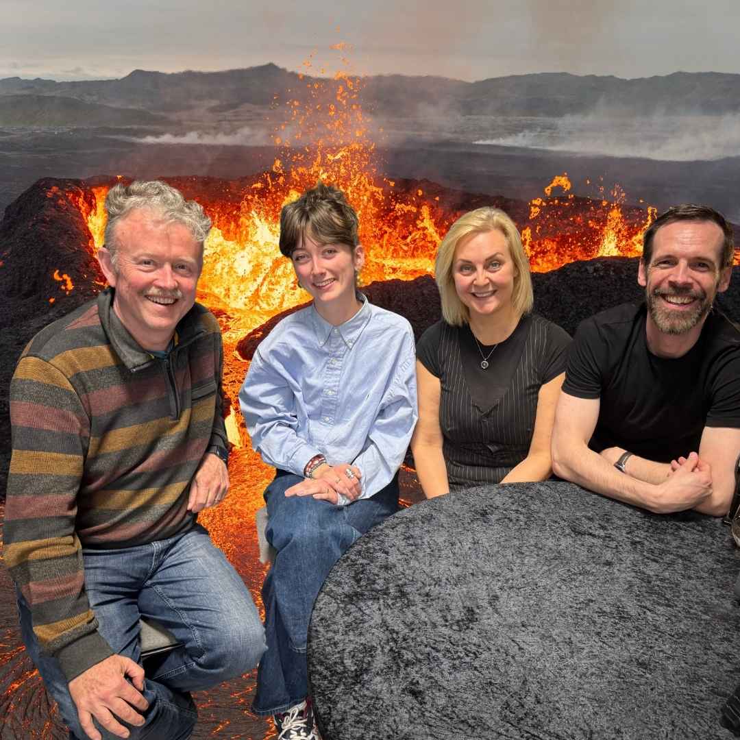 Professor Philip Ringrose, researcher Chloé Delbé, Lava Show founder Ragnhildur Ágústsdóttir (Lady Lava), and Lava Master Iain MacKinnon sitting together in front of a dramatic volcanic lava eruption at Lava Show in Iceland.
