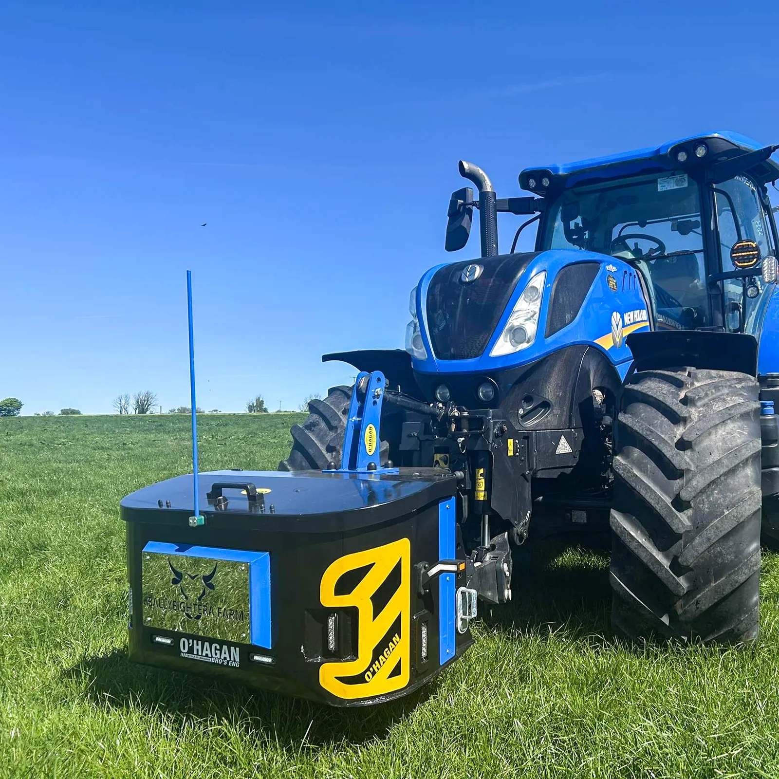 Black and blue work box with black custom name plate attached to a blue new holland tractor in a field