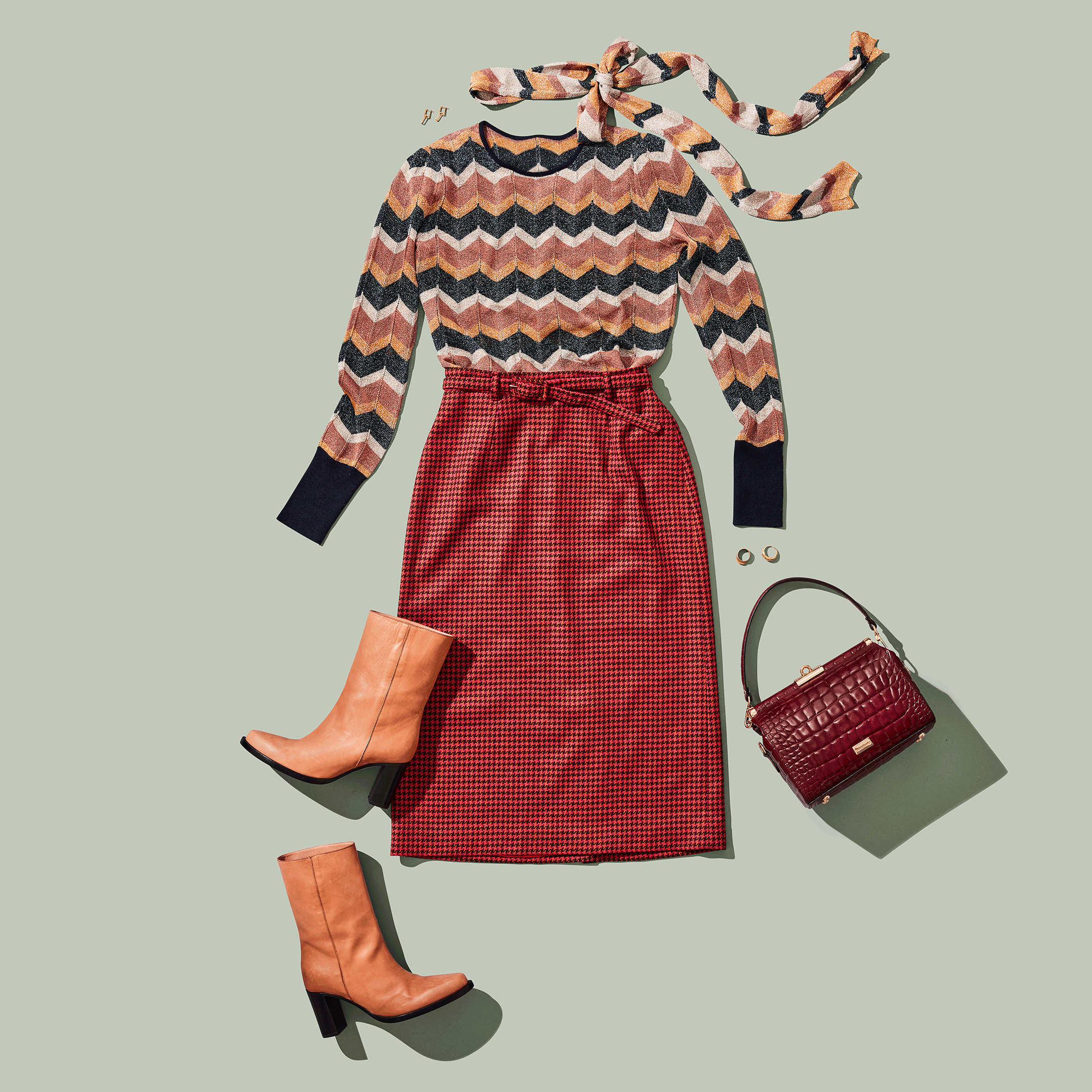 Stylish fall outfit with chevron sweater, red checkered skirt, tan boots, burgundy handbag, and gold jewelry.