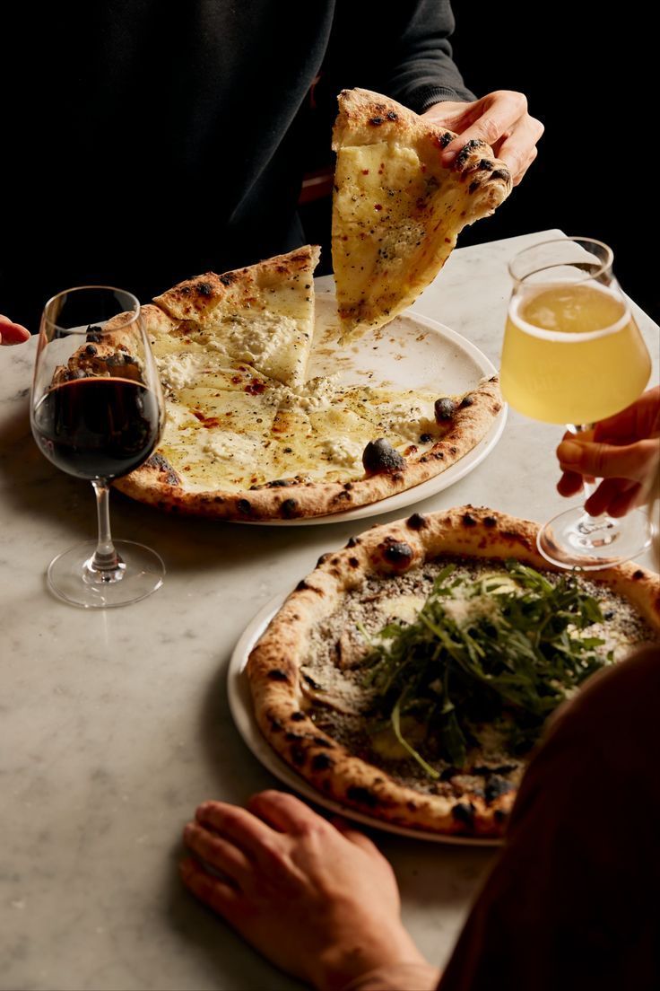 Couple sharing artisan pizza with wine and beer in a cozy upscale restaurant setting, illustrating Dhoom’s curated sound environment and comfortable dining vibe.