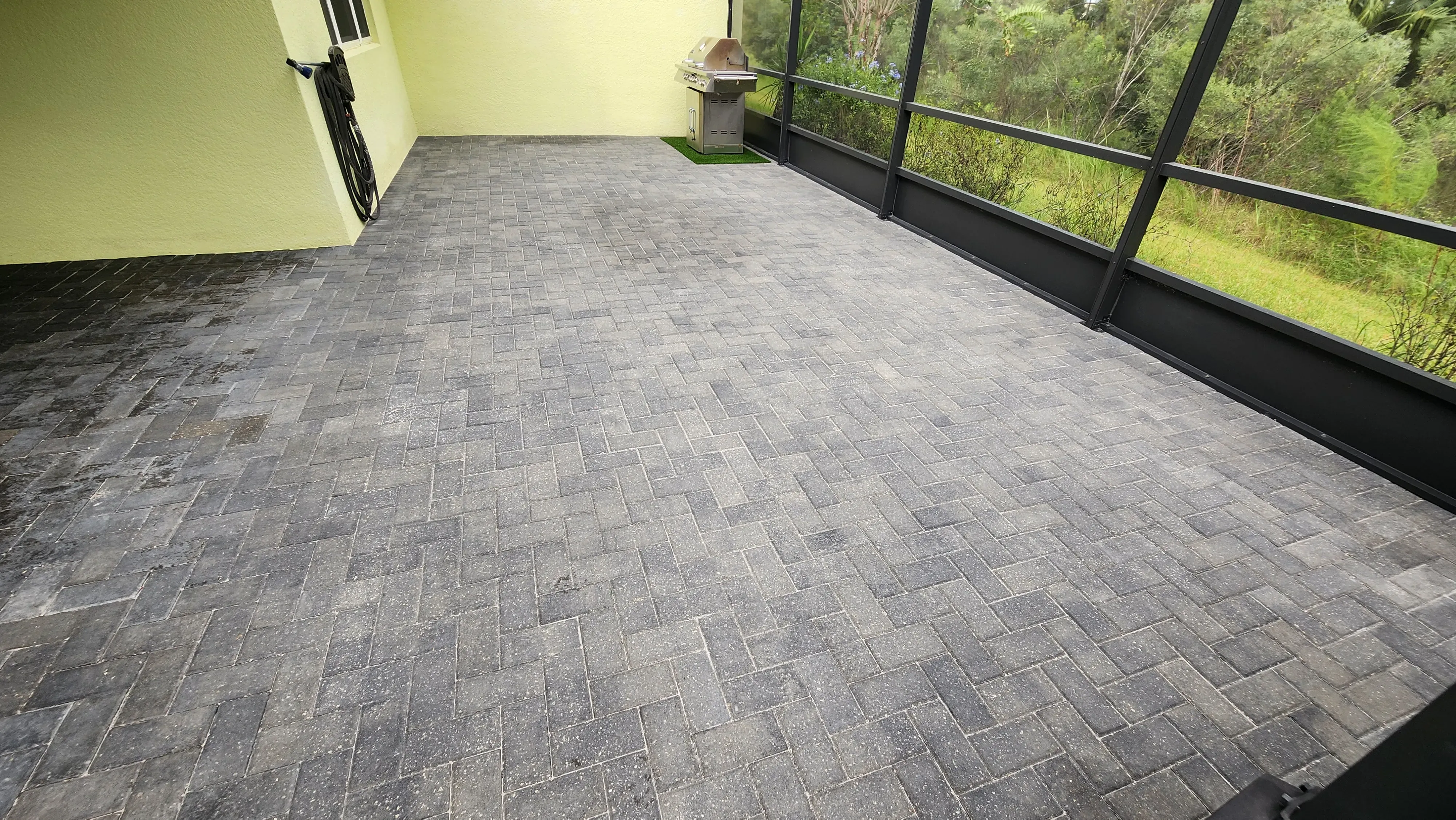 Faded and weed-filled paver patio in Daytona Beach FL before Castle Clean & Seal restoration during dry season