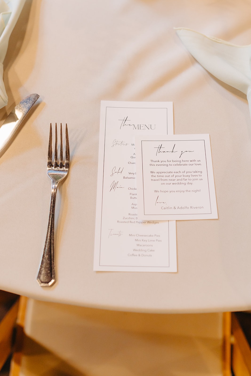 Reception hall filled with round tables, amber chairs, hanging lights, and floral centerpieces.
