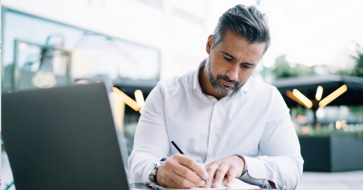 Small business owner reviewing content at his laptop, considering how query fan-out affects whether AI search recommends his business